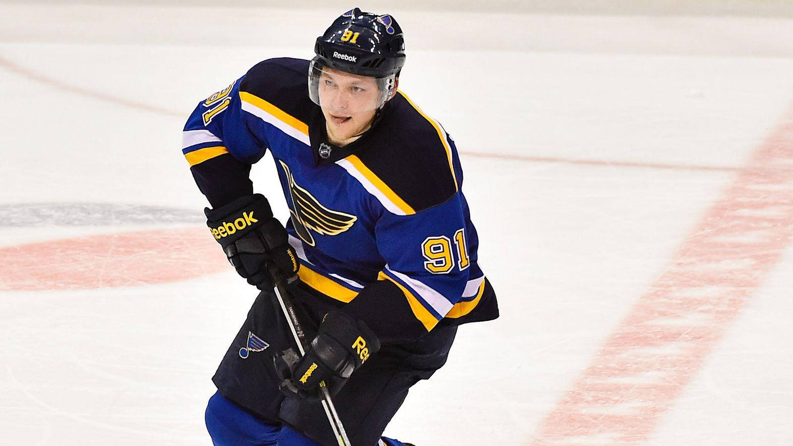 St Louis Blues 桌布 壁紙 — 一名身穿藍金色聖路易斯藍調91號球衣的冰球運動員在冰場上激烈滑行。