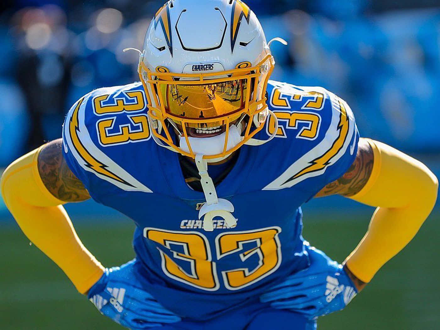 NFL 桌布 壁紙 — 一名身穿藍金色電光隊球衣、號碼33的美式足球員，在陽光明媚的球場上雙手叉腰站立。