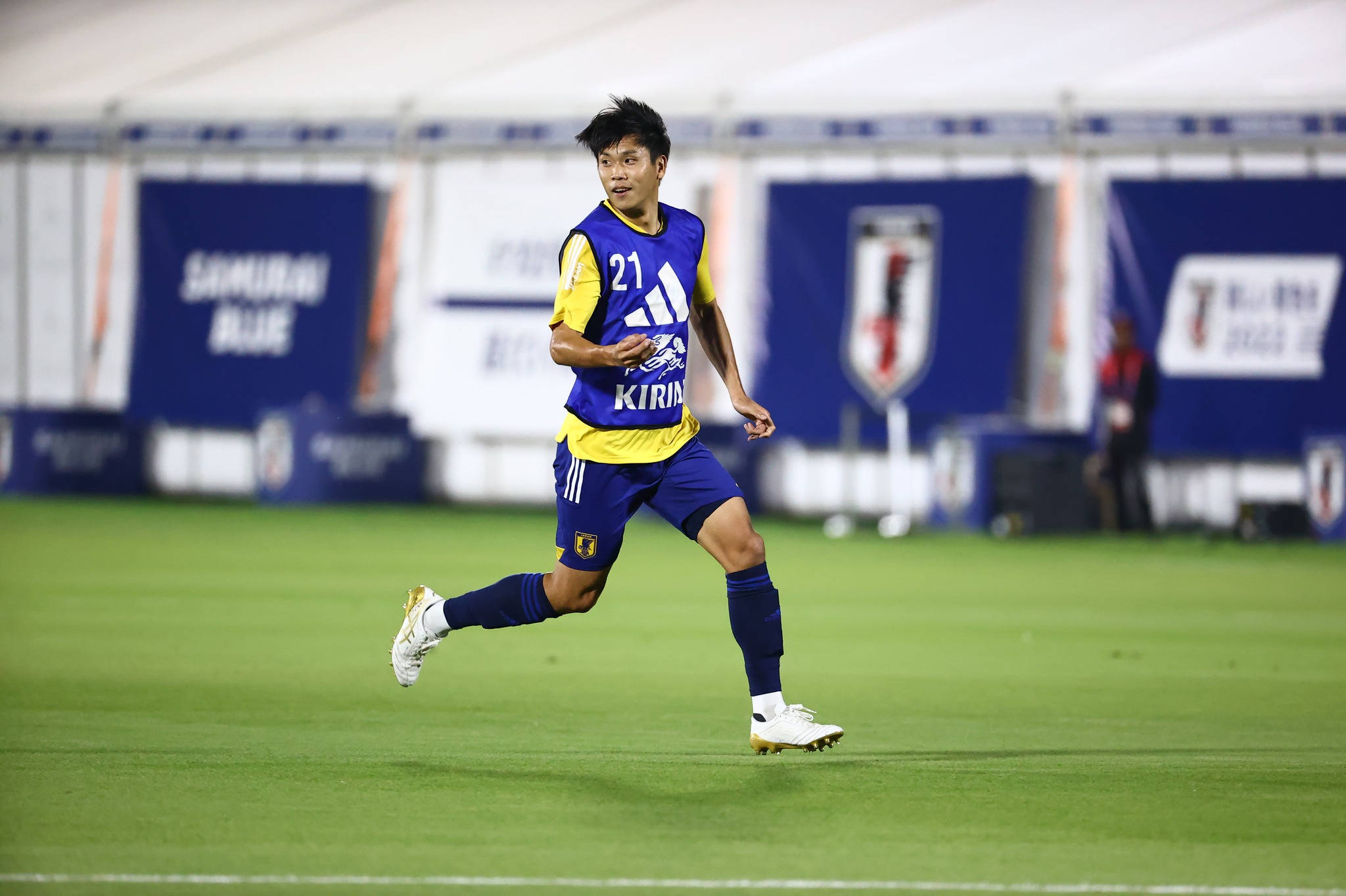 Football Players 桌布 壁紙 — 一名身穿藍黃球衣的足球員在球場燈光下於翠綠草地上飛奔。