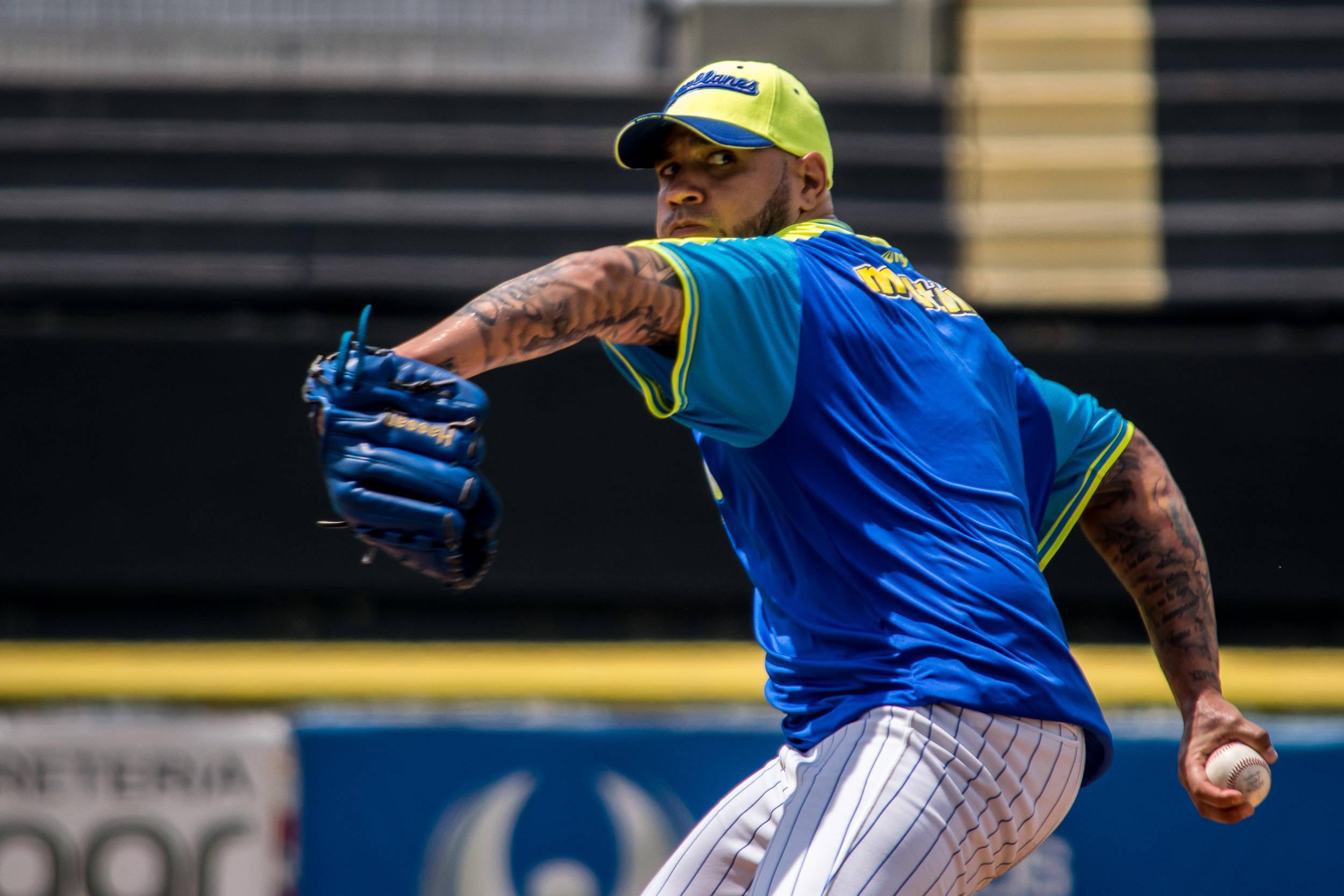 MLB 桌布 壁紙 — 一名身穿藍黃色球衣的棒球投手在明亮的日光下，全神貫注地揮臂投球。