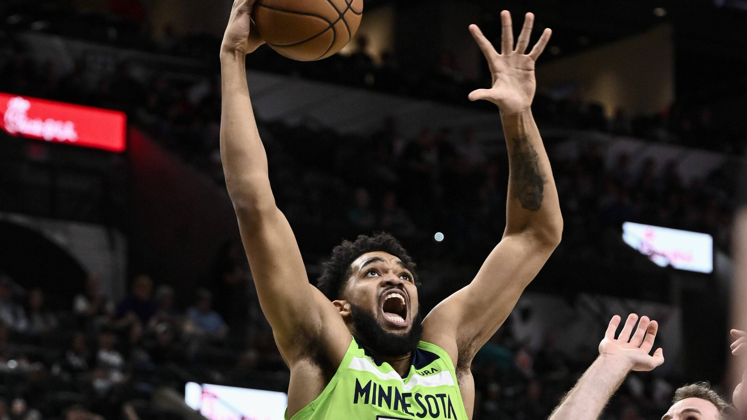 karl-anthony towns 桌布 壁紙 — 一名身穿螢光綠色明尼蘇達球衣的籃球運動員在比賽中高度專注地跳起投籃。