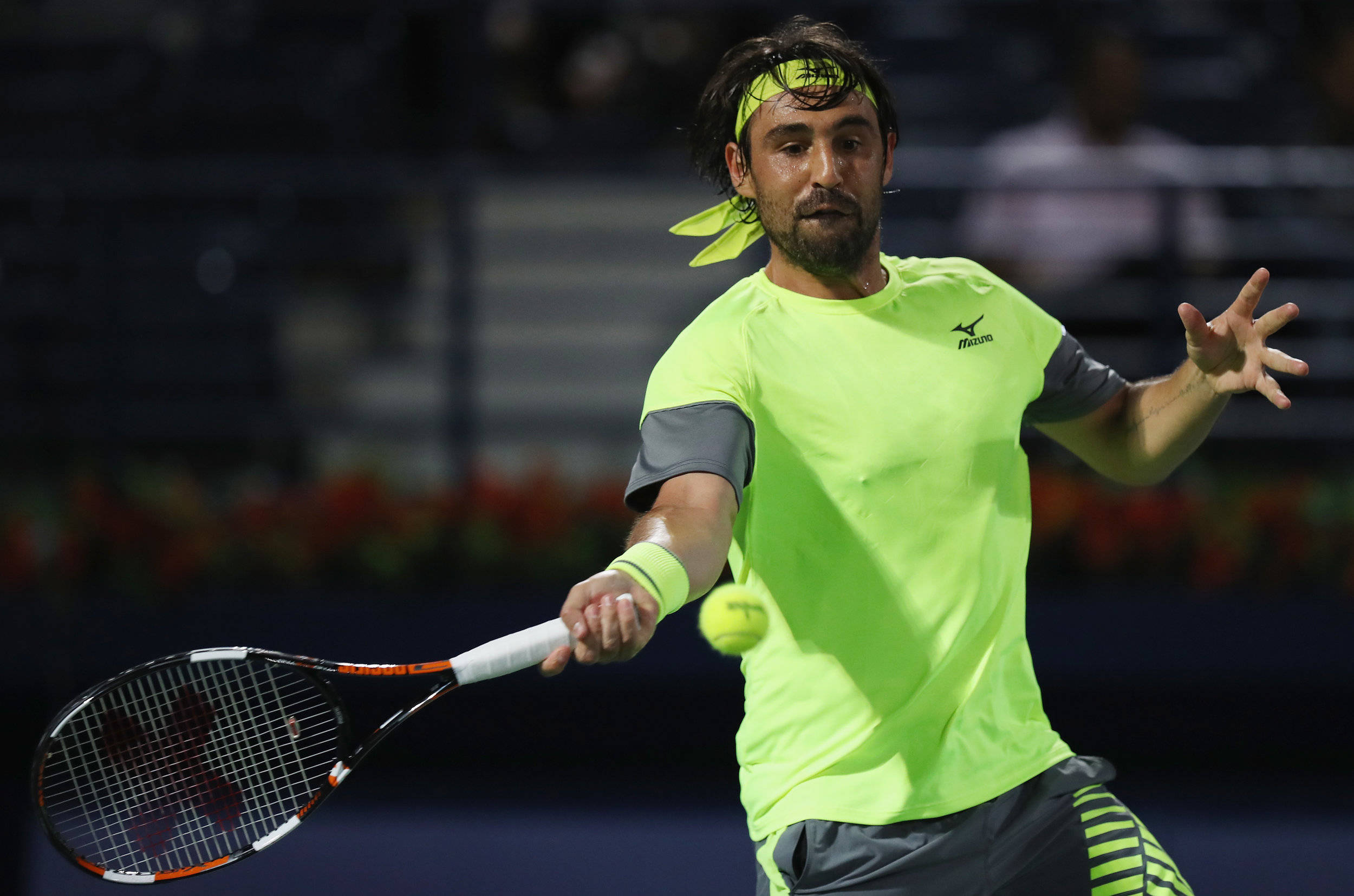 Tennis 桌布 壁紙 — 一名身穿螢光綠色裝備的男網球選手在激烈的夜間比賽中揮拍擊打黃色網球。