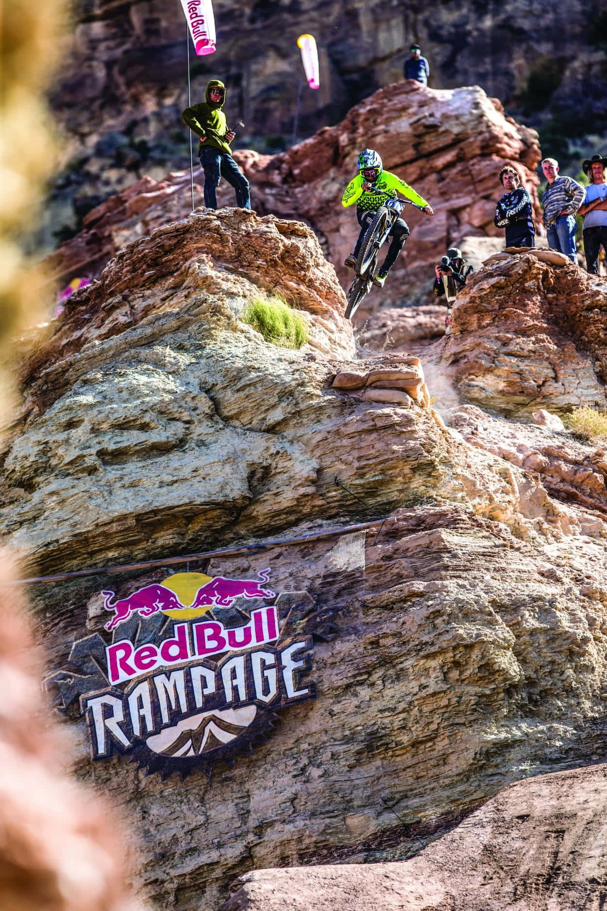 山景 桌布 壁紙 — 一名身穿螢光裝備的山地車手在Red Bull Rampage賽事中，於崎嶇的紅色岩石地形上空飛躍。
