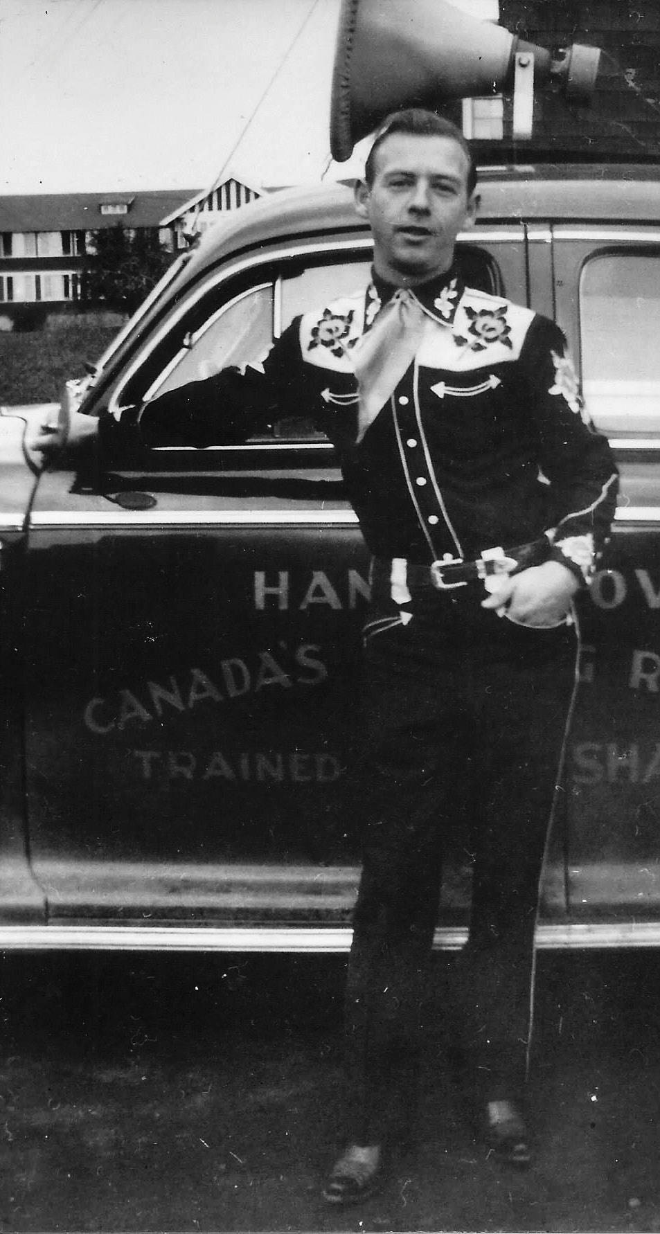artist 桌布 壁紙 — 一名身穿裝飾制服的男人自信地站在一輛帶有「CANADA'S TRAINED」字樣的復古汽車旁。