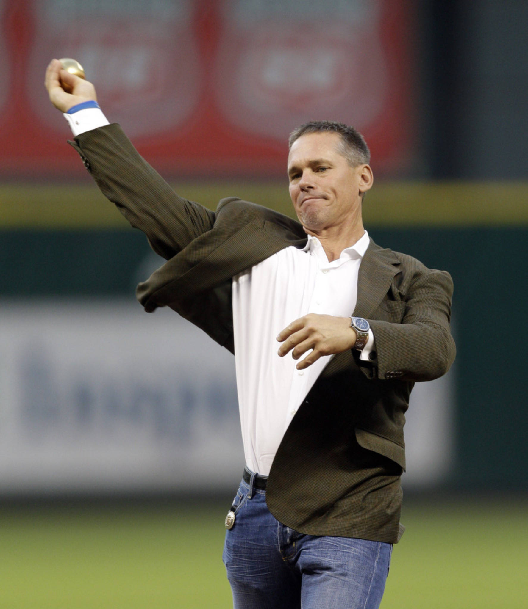Craig Biggio 桌布 壁紙 — 一名身穿西裝外套和牛仔褲的男子在球場上的人工燈光下準備投擲棒球。