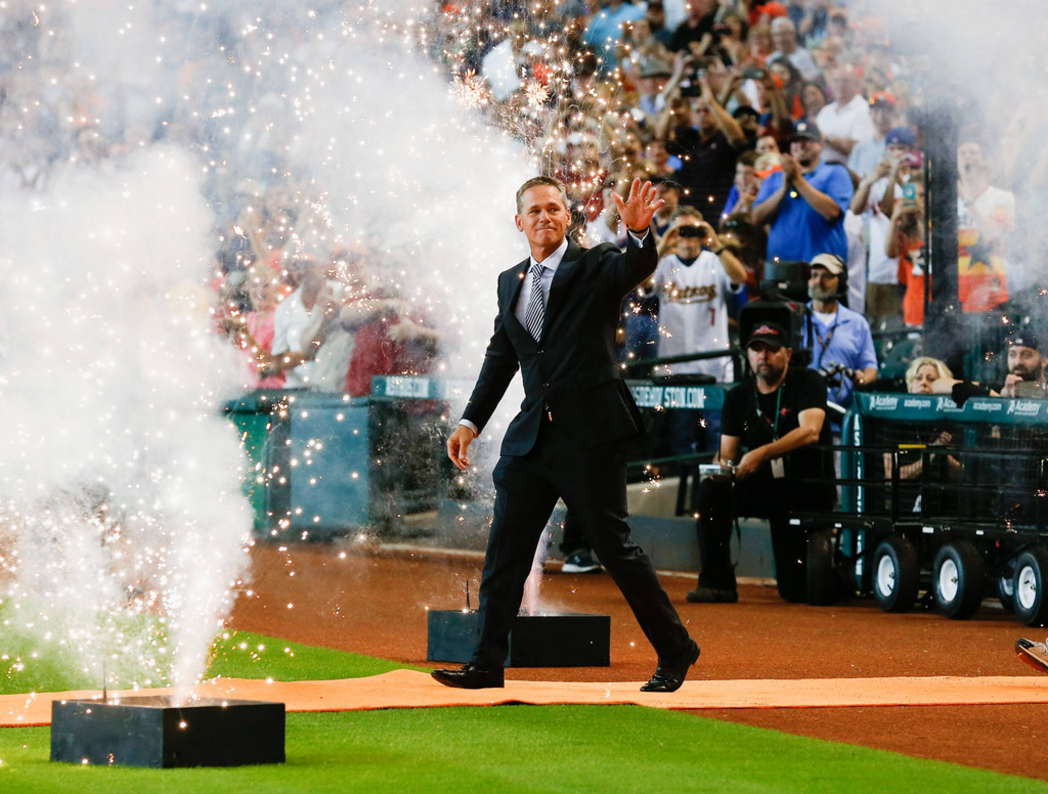 Craig Biggio 桌布 壁紙 — 一名身穿西裝的男子在夜間的棒球場上向歡呼的粉絲揮手，周圍煙花綻放。
