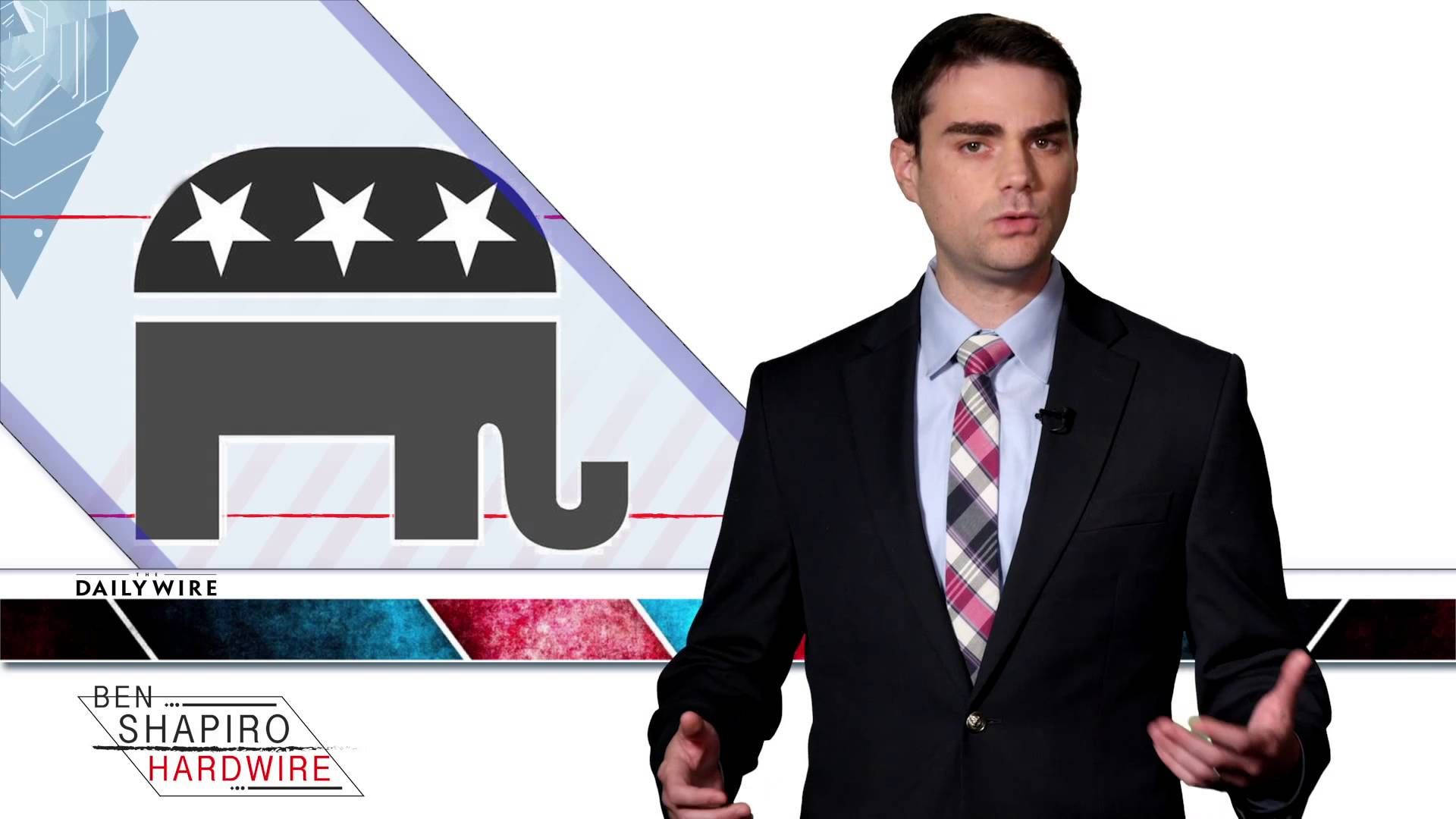 Ben Shapiro 桌布 壁紙 — 一名身穿西裝的男子在帶有共和黨大象標誌和DailyWire品牌的圖形旁邊做手勢。