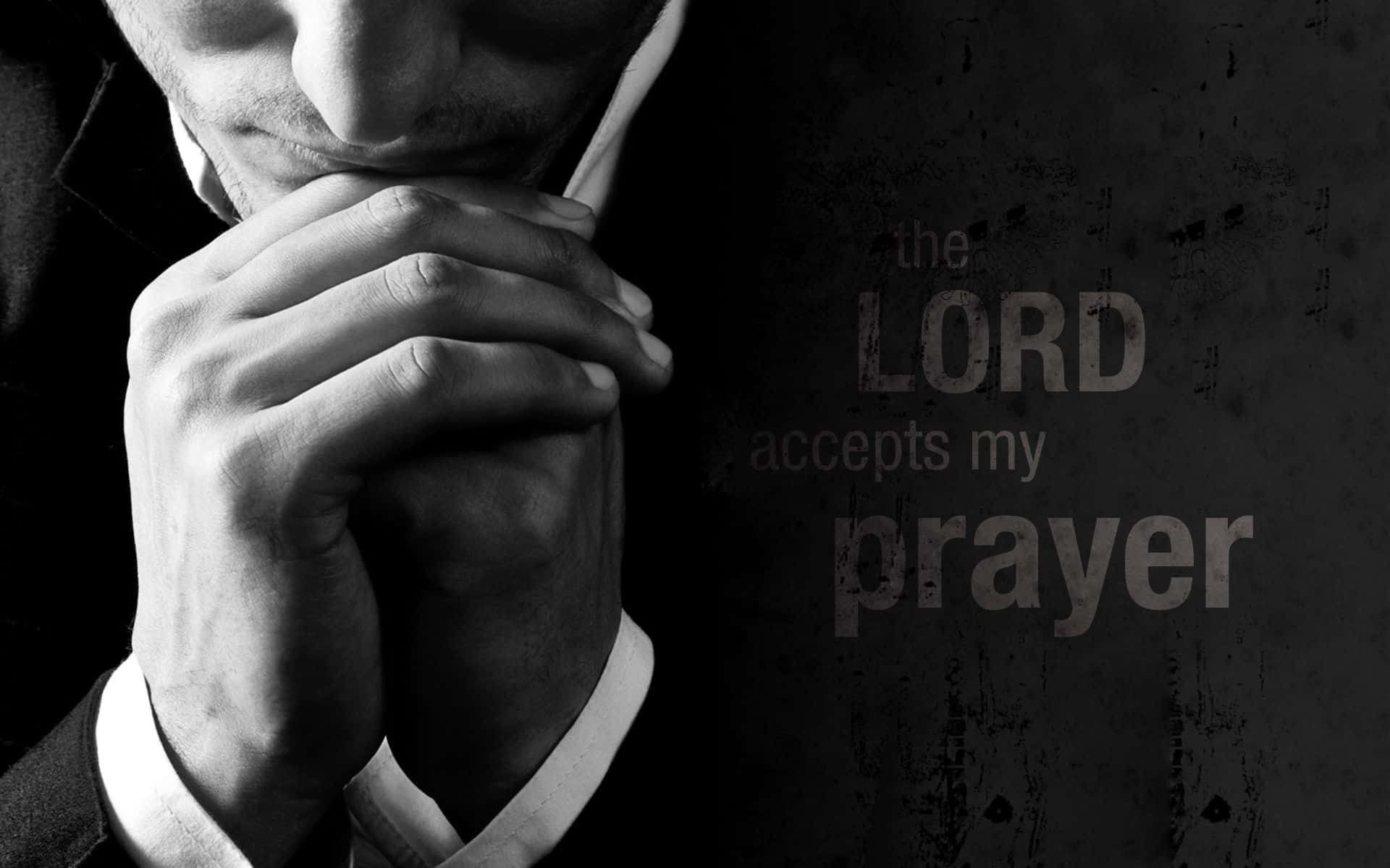 Praying 桌布 壁紙 — 一名身穿西裝的男子在深色紋理牆前合十祈禱，牆上寫著「主接納我的禱告」。