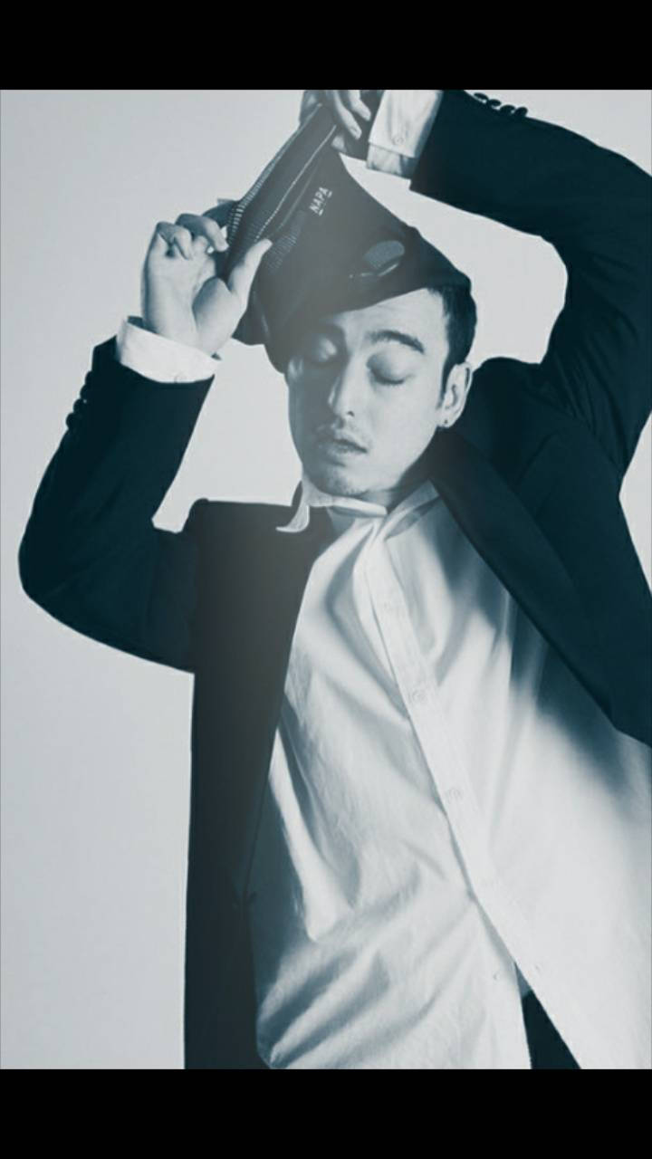 joji 桌布 壁紙 — 一名身穿西裝的男子在純白背景前戲劇性地將書高舉過頭，形成高對比度的黑白照片。