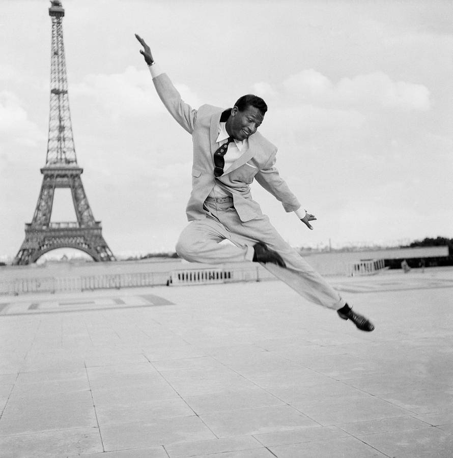 Eiffel Tower 桌布 壁紙 — 一名身穿西裝的男子在艾菲爾鐵塔前歡樂跳躍，永恆的黑白照片。