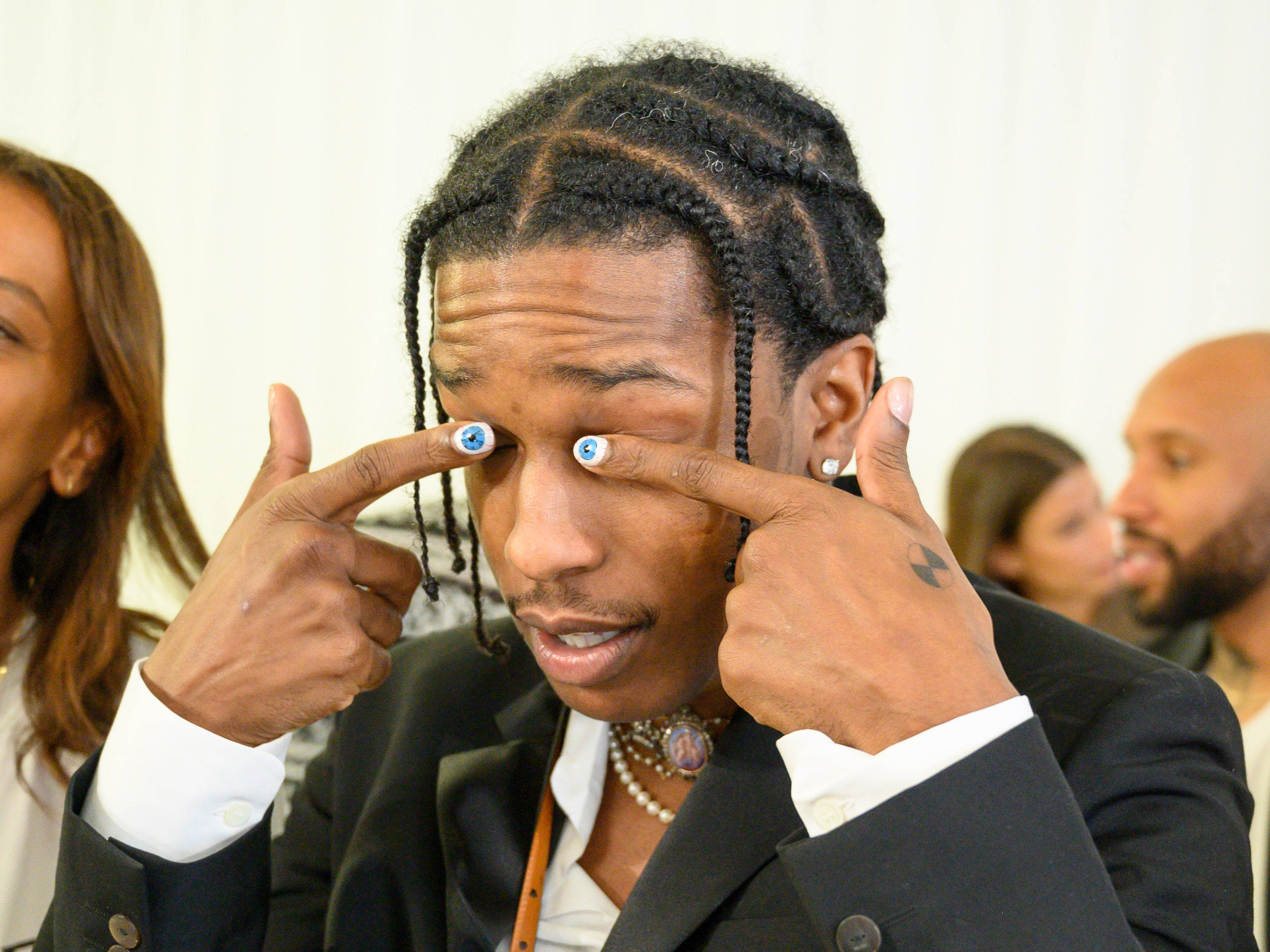 rocky 桌布 壁紙 — 一名身穿西裝的男子坐在活動中，指著他佩戴藍色寶石隱形眼鏡的眼睛。