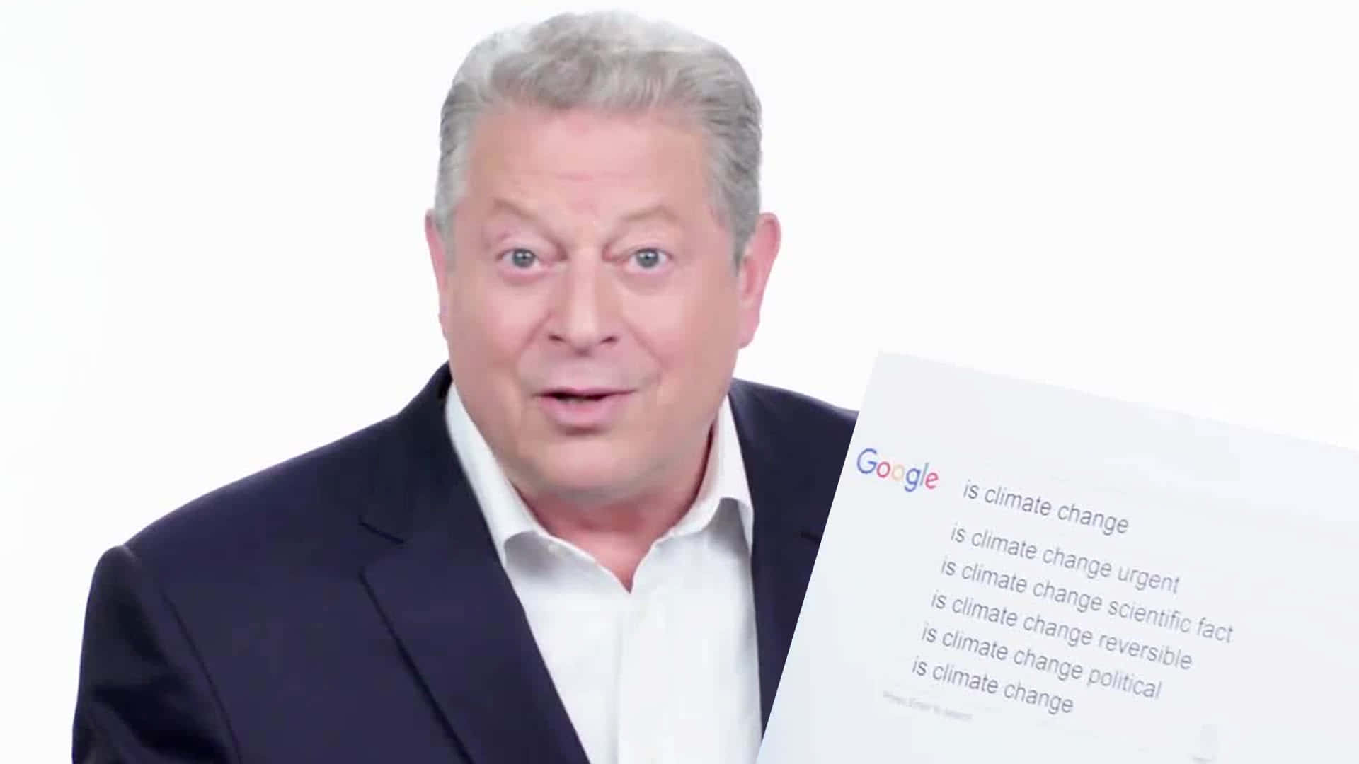 Celebrity 桌布 壁紙 — 一名身穿西裝的男子手持一份Google搜尋結果表，上面列出氣候變遷問題，背景為純白色。