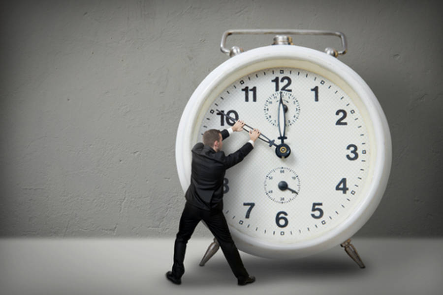 times up 桌布 壁紙 — 一名身穿西裝的男子正努力將一個巨大的白色鬧鐘推向一面純灰色的牆壁。