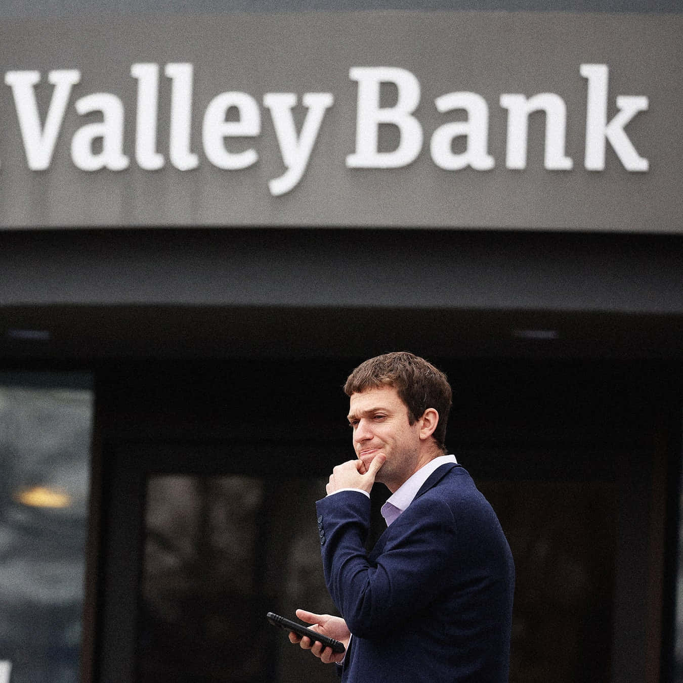 Bank 桌布 壁紙 — 一名身穿西裝的男子站在Valley Bank外面，若有所思地看著手機。