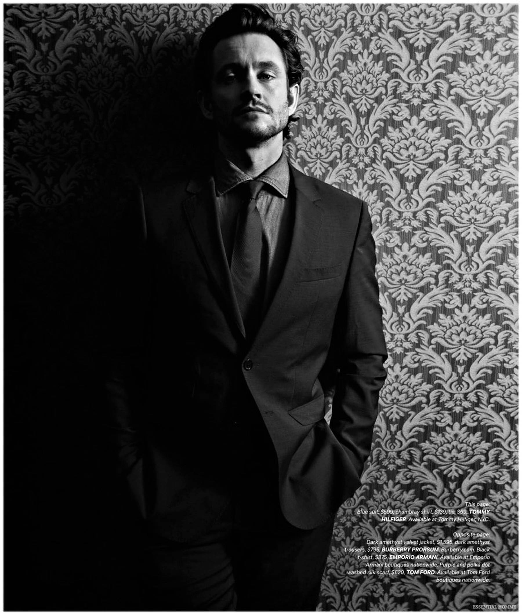 Hugh Dancy 桌布 壁紙 — 一名身穿西裝的男子站在華麗的錦緞壁紙前，呈現高對比度的黑白肖像。