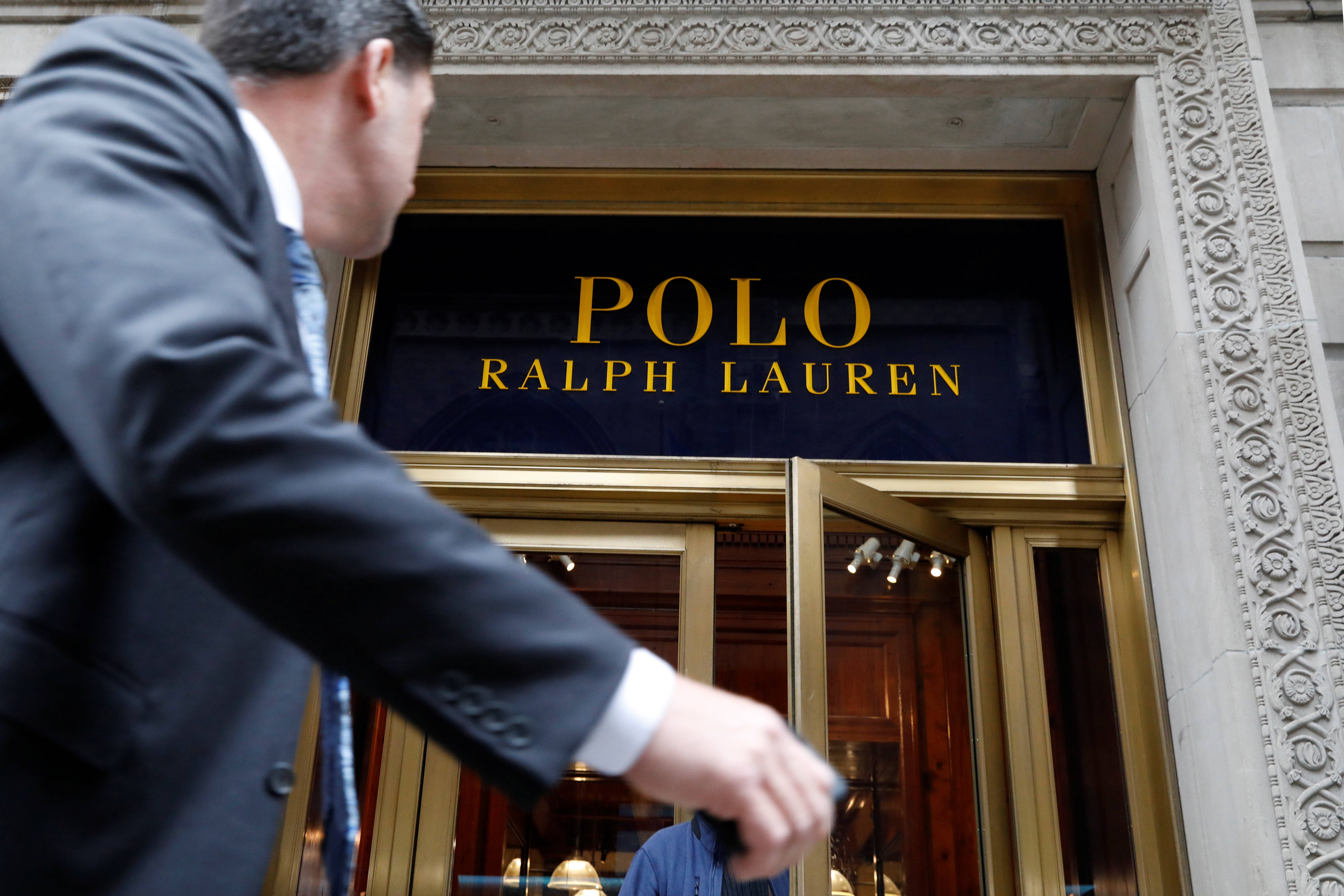 ralph lauren 桌布 壁紙 — 一名身穿西裝的男子走過Ralph Lauren商店華麗的入口，入口處有金色字體和精緻的石頭建築。