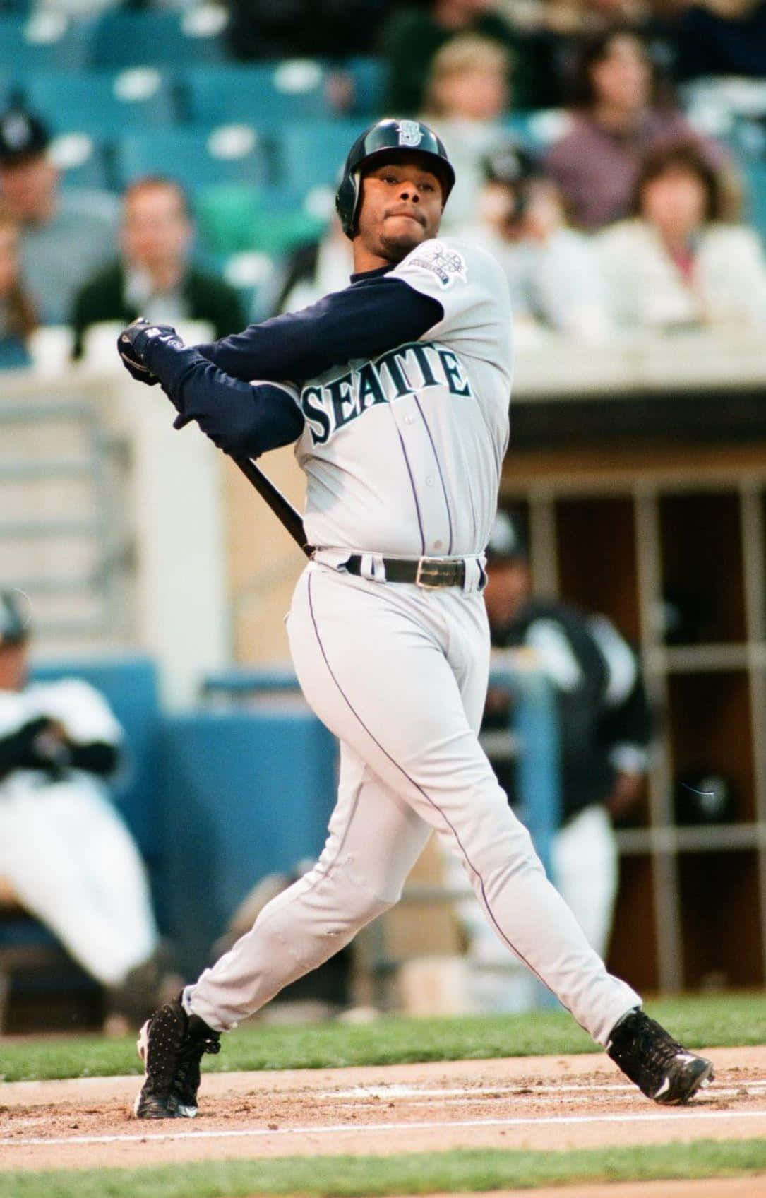 baseball bat 桌布 壁紙 — 一名身穿西雅圖球衣的棒球選手在球場燈光下比賽時，專注地揮動球棒。