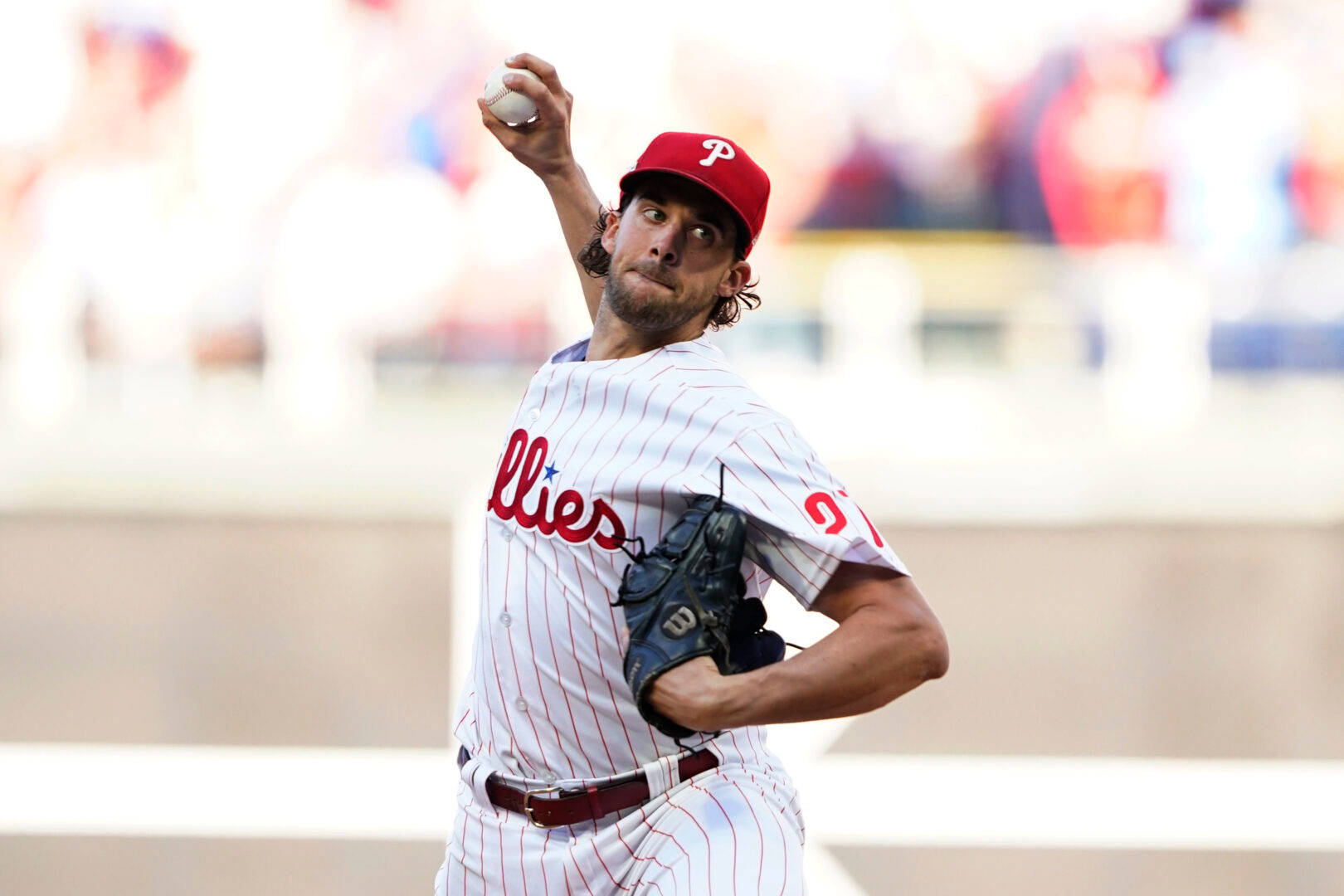 MLB 桌布 壁紙 — 一名身穿費城人隊球衣的棒球投手在日間比賽中全神貫注地揮臂投球。