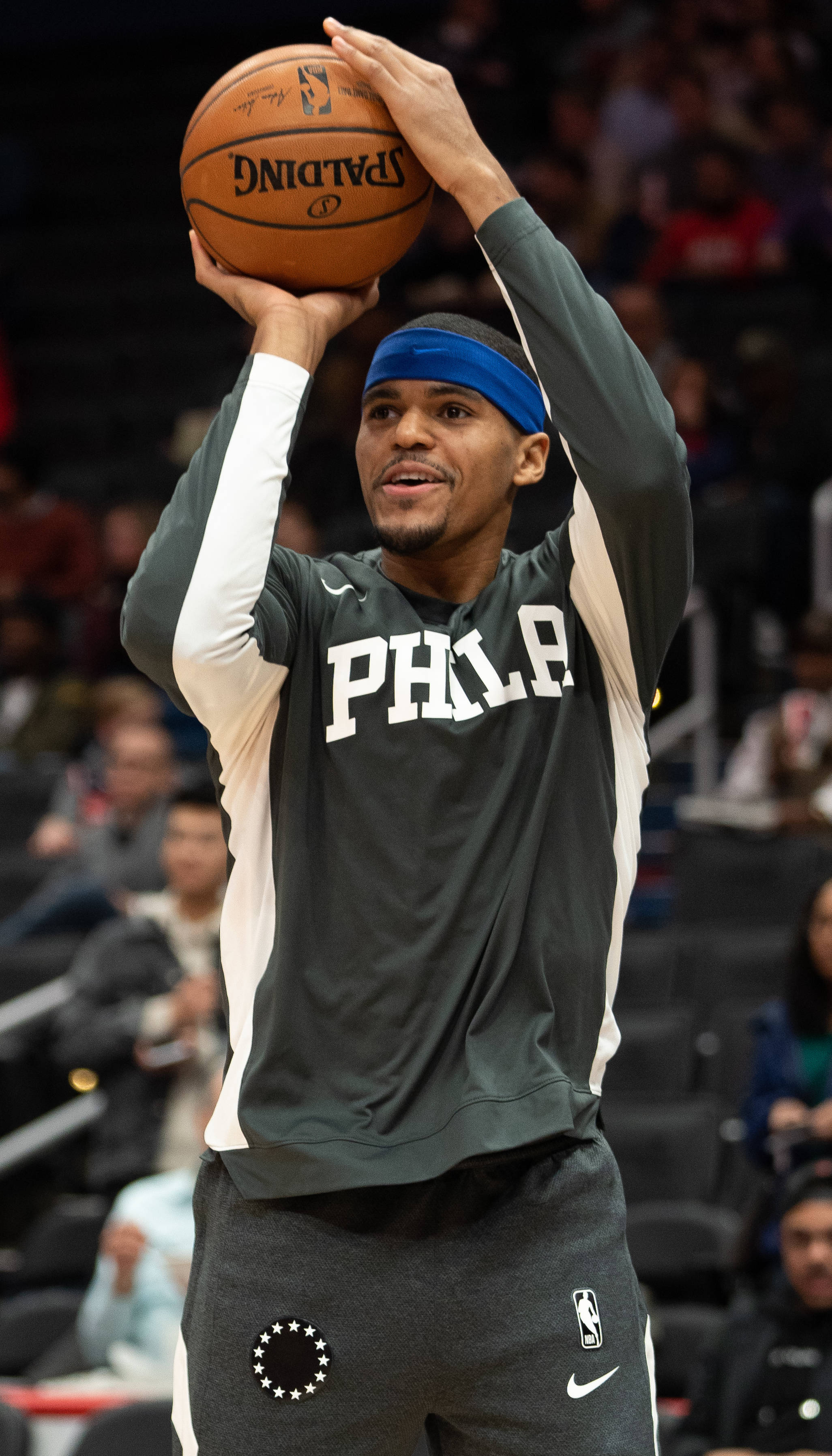NBA 桌布 壁紙 — 一名身穿費城球衣的籃球運動員在比賽中準備投擲Spalding籃球，背景是模糊的觀眾。