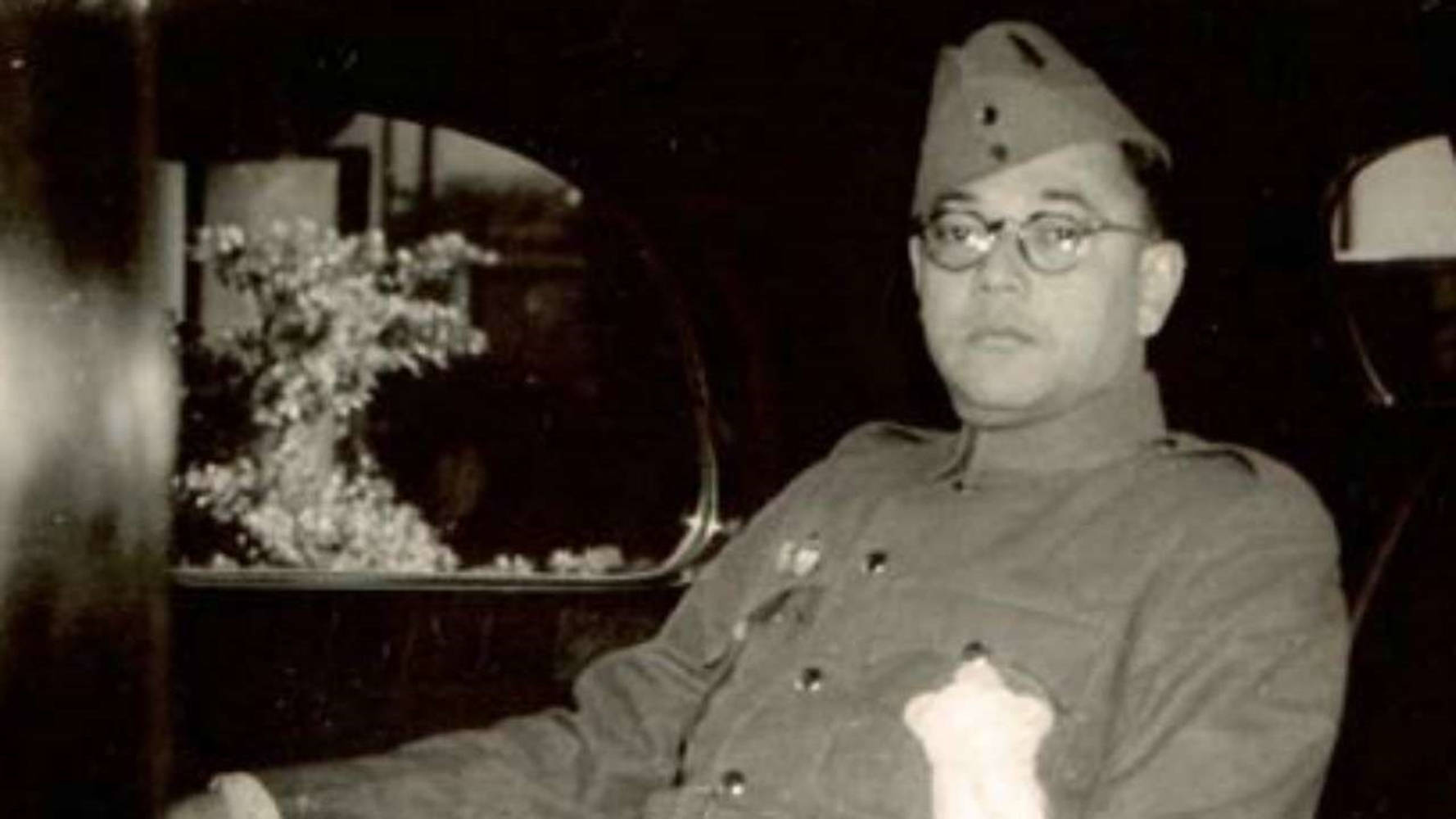 印度軍隊 桌布 壁紙 — 一名身穿軍裝、戴眼鏡的男子坐在一輛老爺車內，透過車窗可以看到花卉佈置。