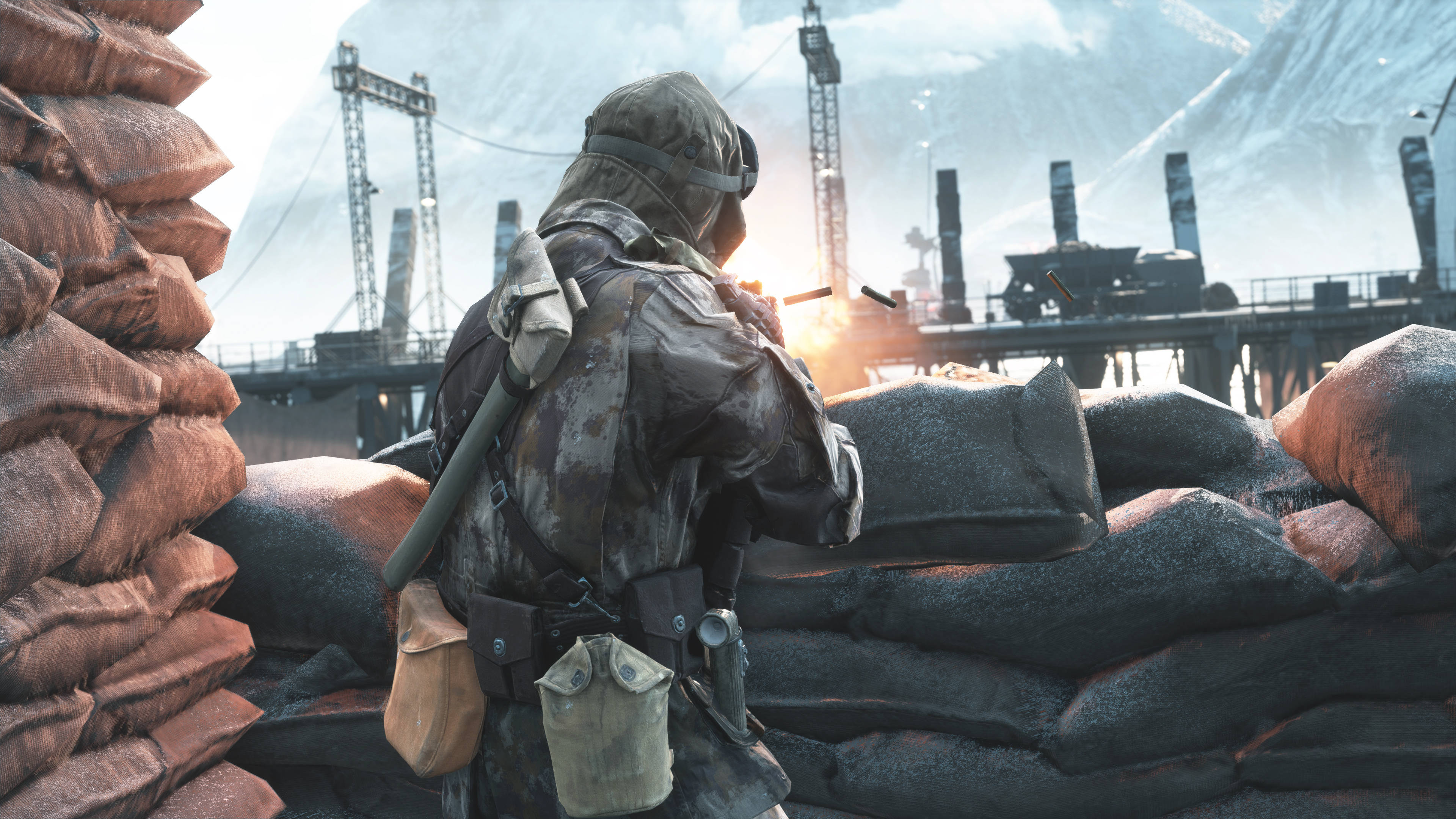 combat 桌布 壁紙 — 一名身穿迷彩服的士兵在沙包後方掩護，爆炸照亮了白雪覆蓋的工業戰場。