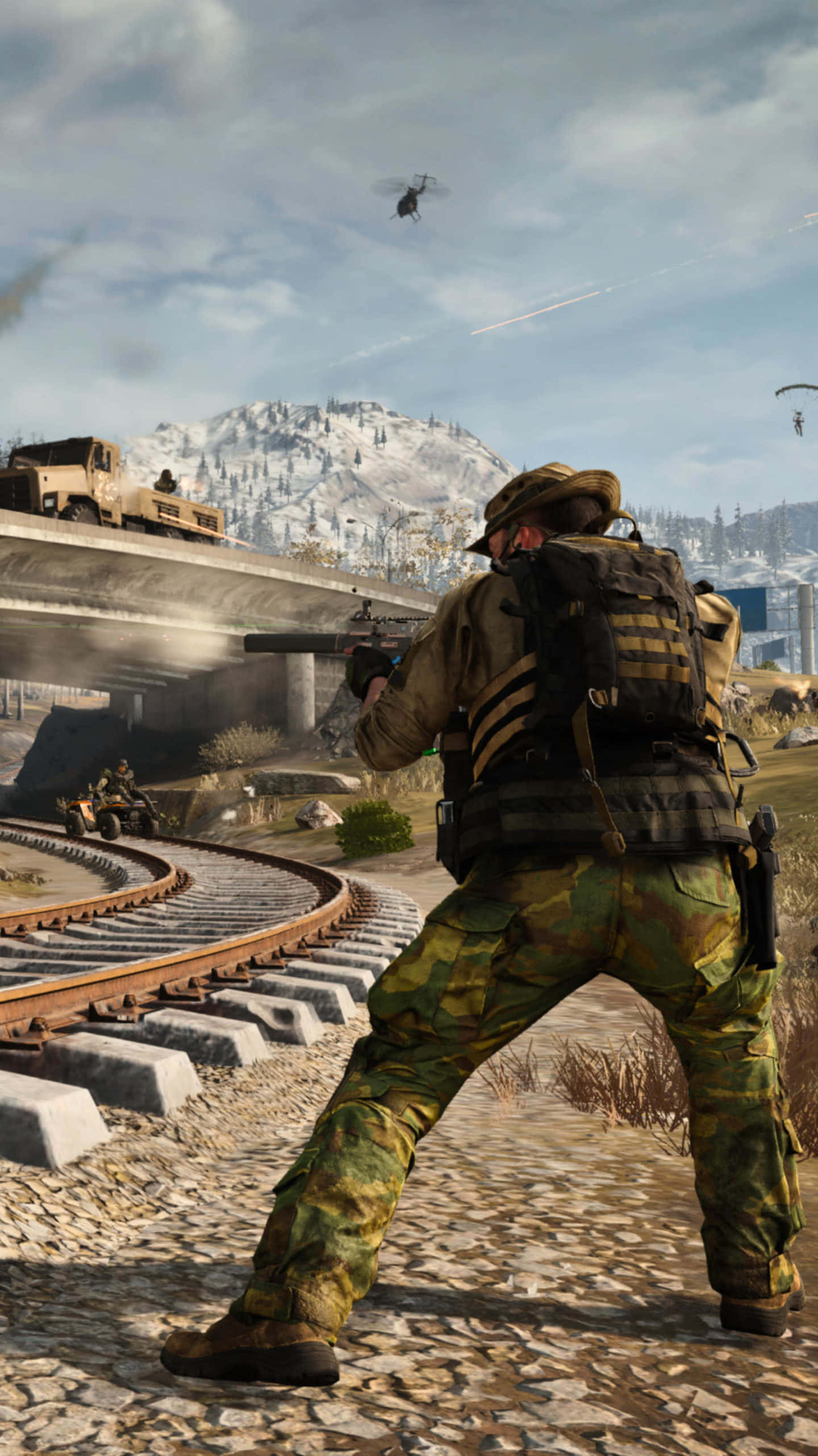 Call Of Duty 2020 桌布 壁紙 — 一名身穿迷彩服的士兵在火車軌道附近瞄準步槍，一架直升機在白雪覆蓋的山地戰場上空飛過。