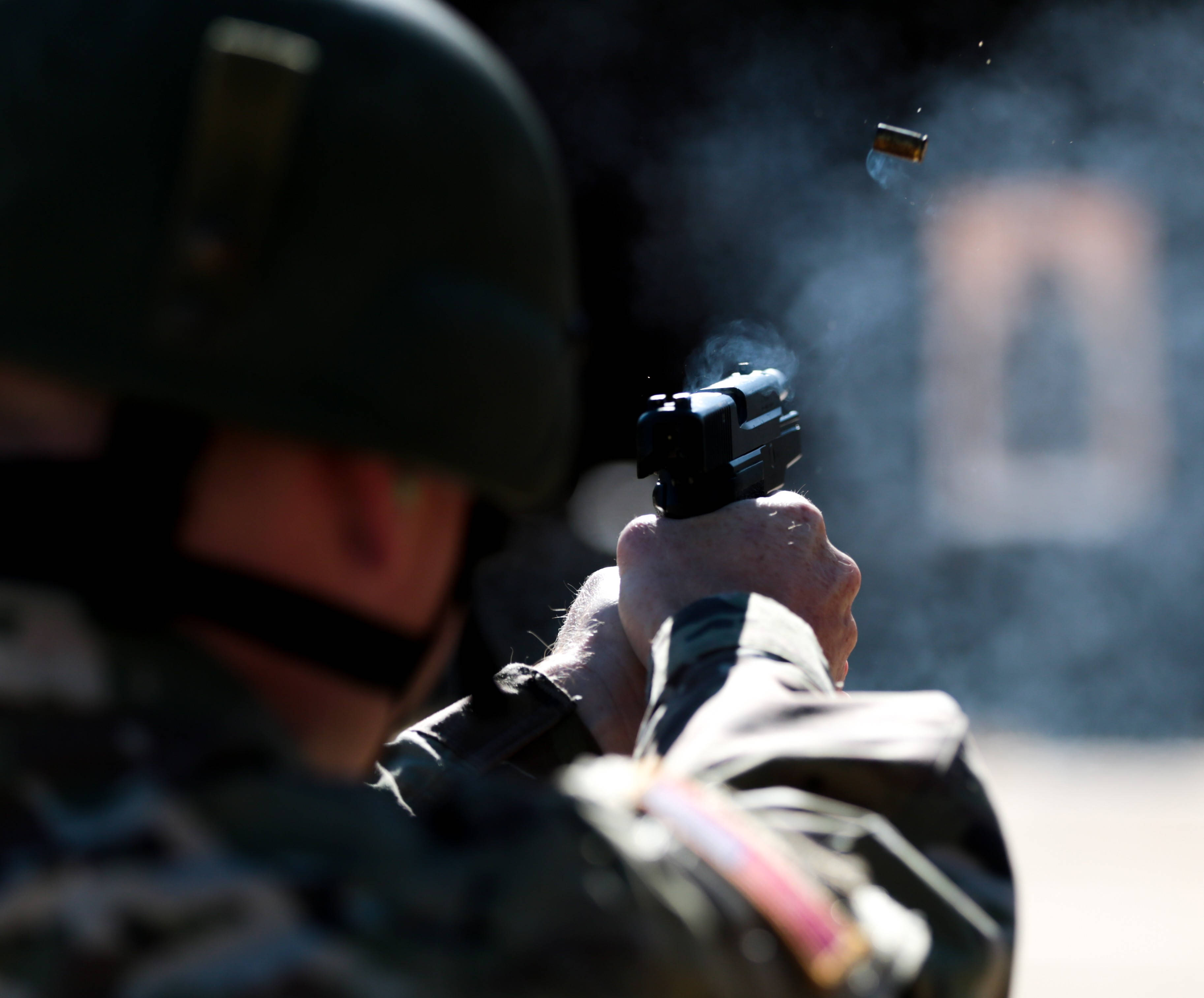 Shooting 桌布 壁紙 — 一名身穿迷彩服的士兵開槍射擊，一顆用過的彈殼在空中飛過，背景是模糊的目標。