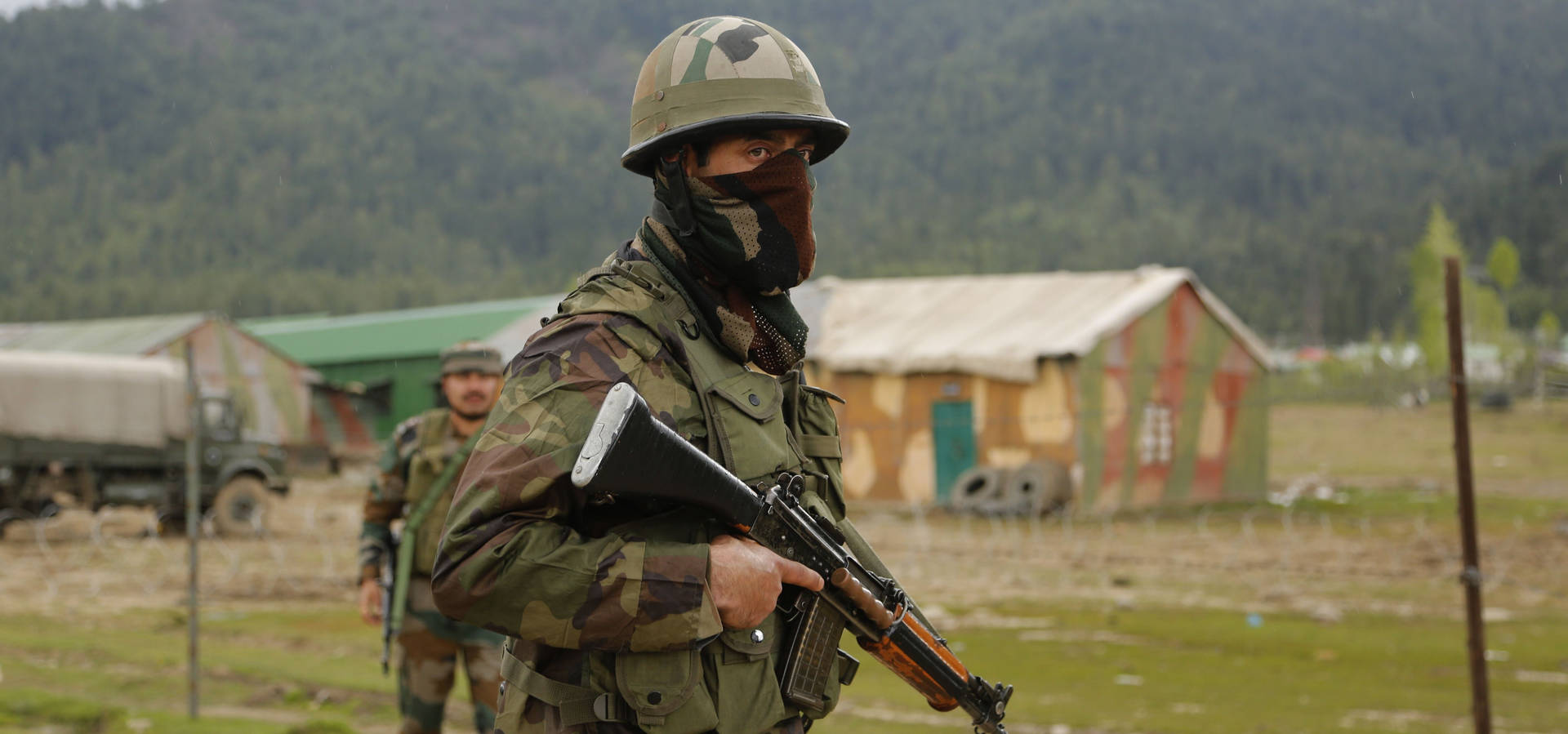 身穿迷彩服的士兵在樹林地區的軍用帳篷附近持步槍。 — 印度軍隊 壁紙