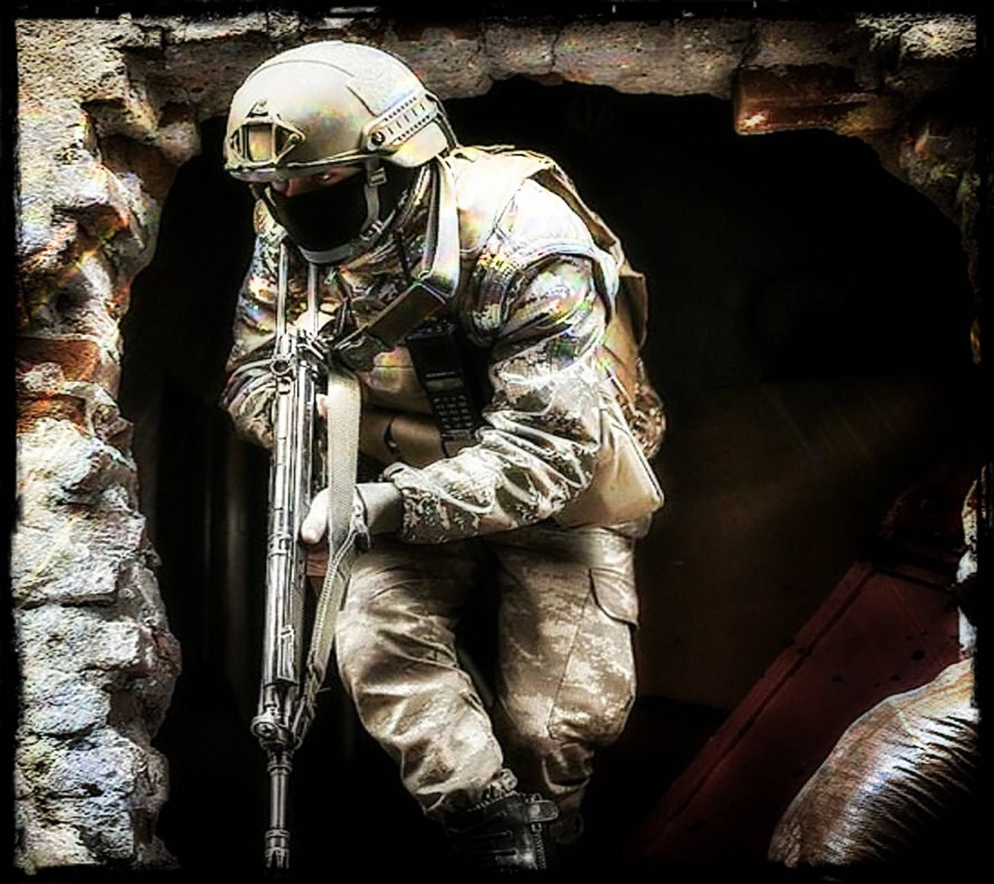 軍隊 桌布 壁紙 — 一名身穿迷彩裝備和頭盔的士兵在黑暗的石拱門中持步槍蹲下。