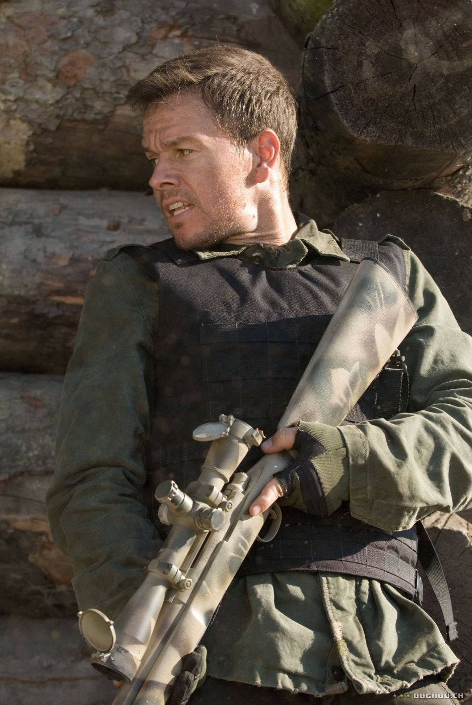 Mark Wahlberg 桌布 壁紙 — 一名身穿迷彩裝備的士兵在明亮的日光下，以堆疊的原木為背景，手持帶瞄準鏡的步槍。