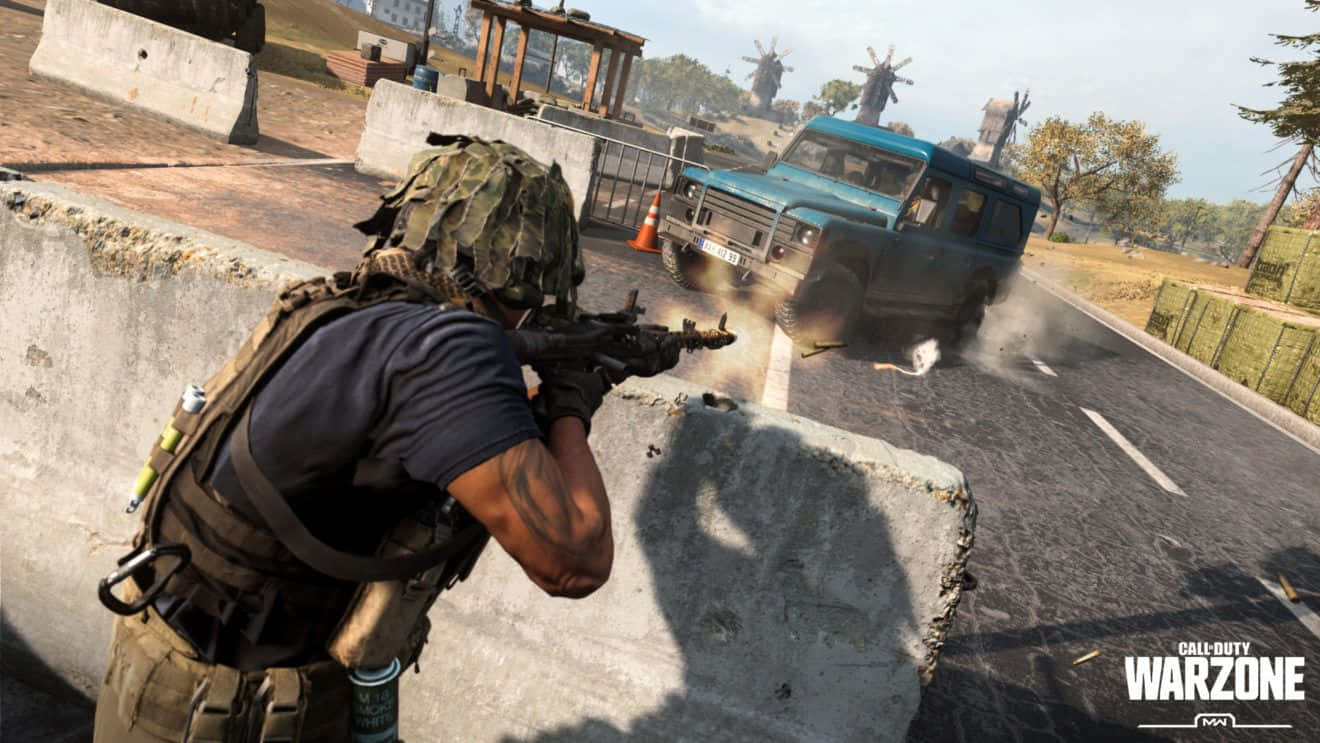 Call Of Duty Vehicles 桌布 壁紙 — 一名身穿迷彩裝備的士兵在混凝土屏障後開步槍，一輛藍色卡車在陽光照耀的道路上爆炸。