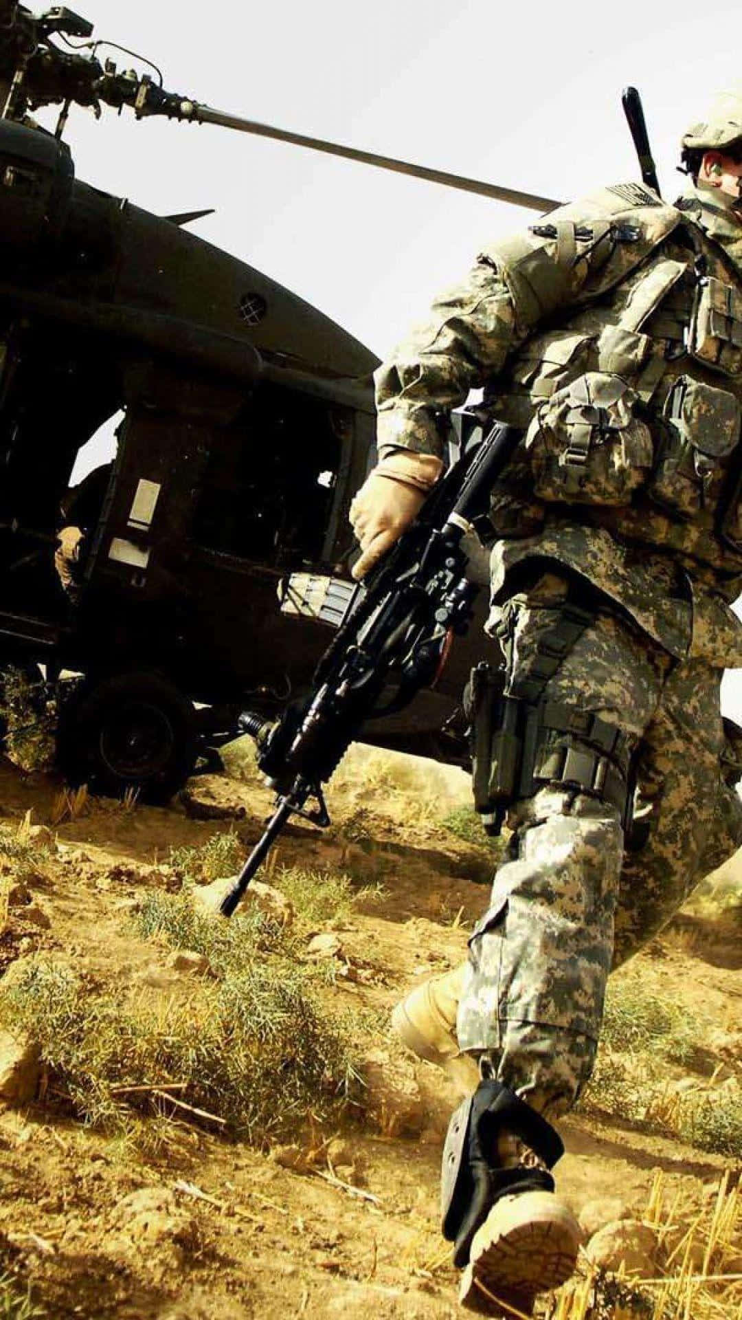 軍事動圖 桌布 壁紙 — 一名身穿迷彩裝備的士兵持步槍向前行進，一架軍用直升機在塵土飛揚的沙漠景觀中盤旋於其後。