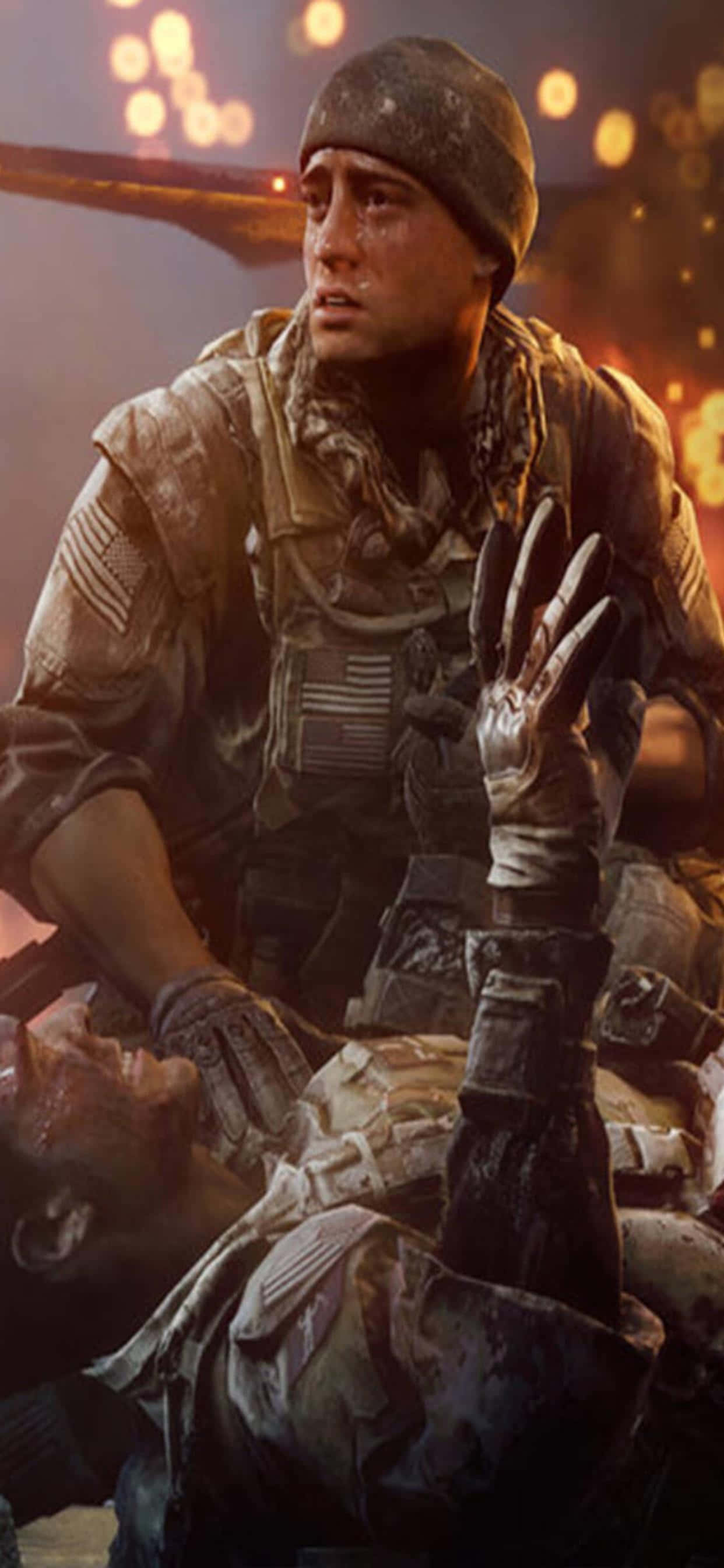 iPhone Xs Max Battlefield 4 桌布 壁紙 — 一名身穿迷彩裝備的士兵跪在倒下的戰友旁邊，背景是燃燒的戰場，橙色爆炸閃爍。