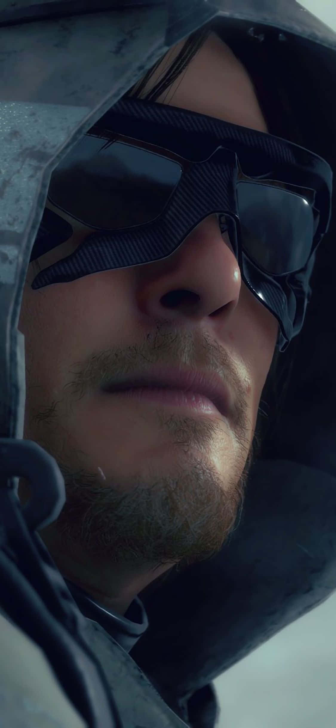 iPhone Xs Death Stranding 桌布 壁紙 — 一名身穿連帽外套和深色護目鏡、表情嚴肅的男子特寫。
