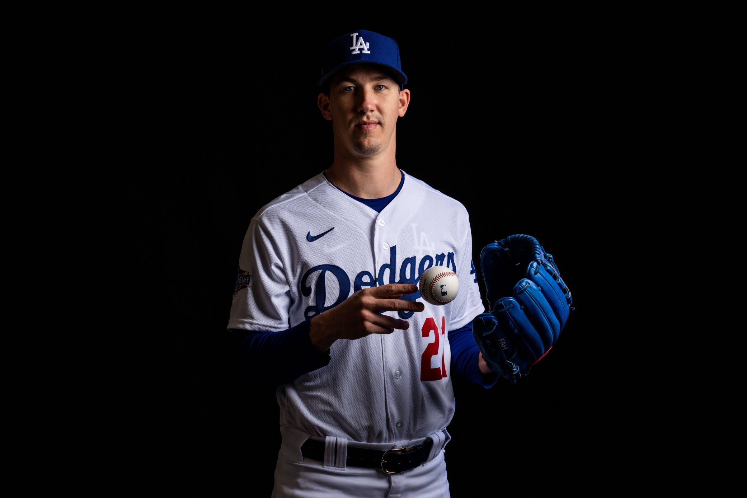 walker buehler 桌布 壁紙 — 一名身穿道奇隊制服的棒球運動員，在純黑色背景前拿著一顆球和手套。