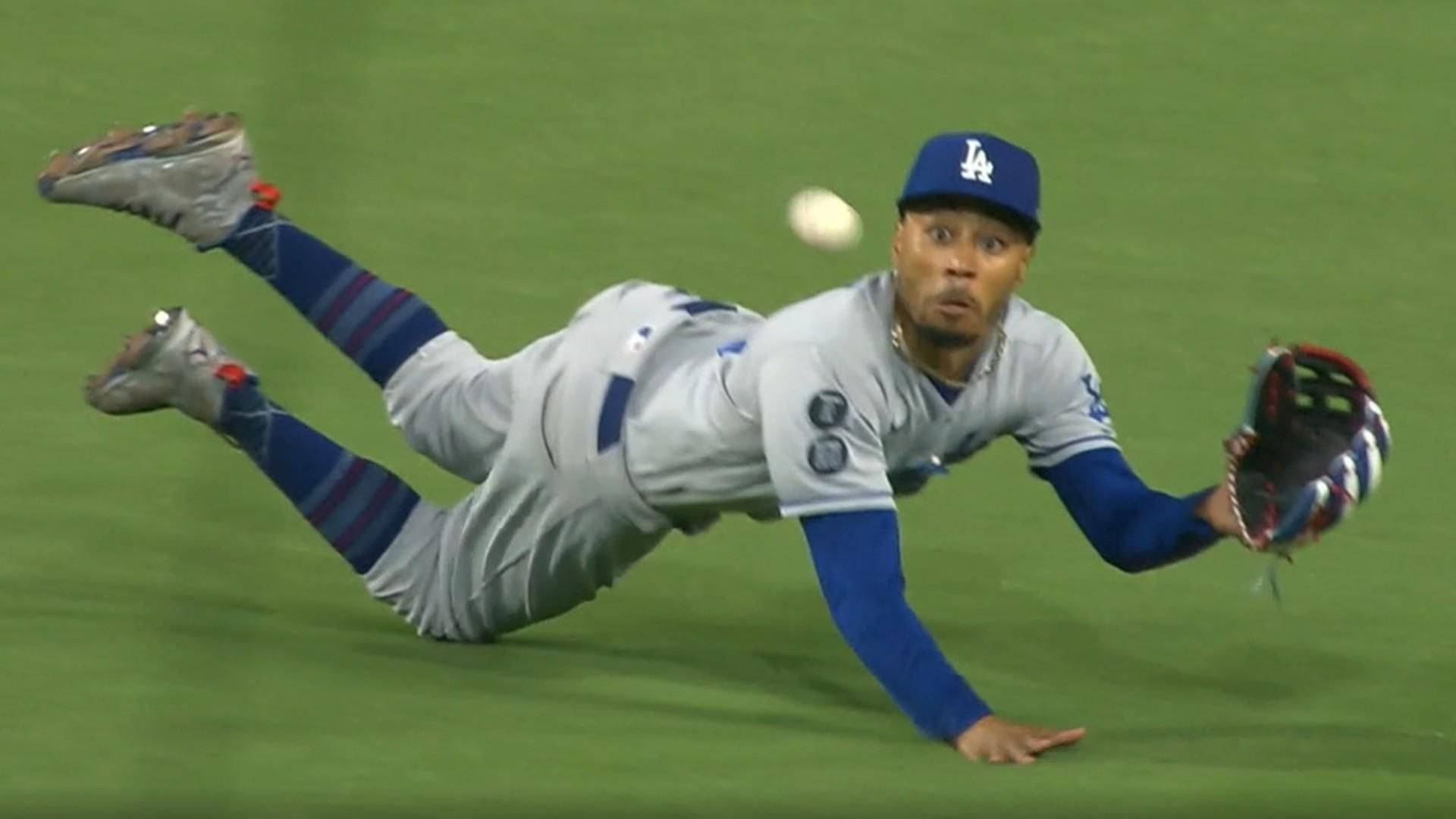 Mookie Betts 桌布 壁紙 — 一名身穿道奇隊球衣的棒球選手在綠色場地上飛撲，伸手用手套接球。
