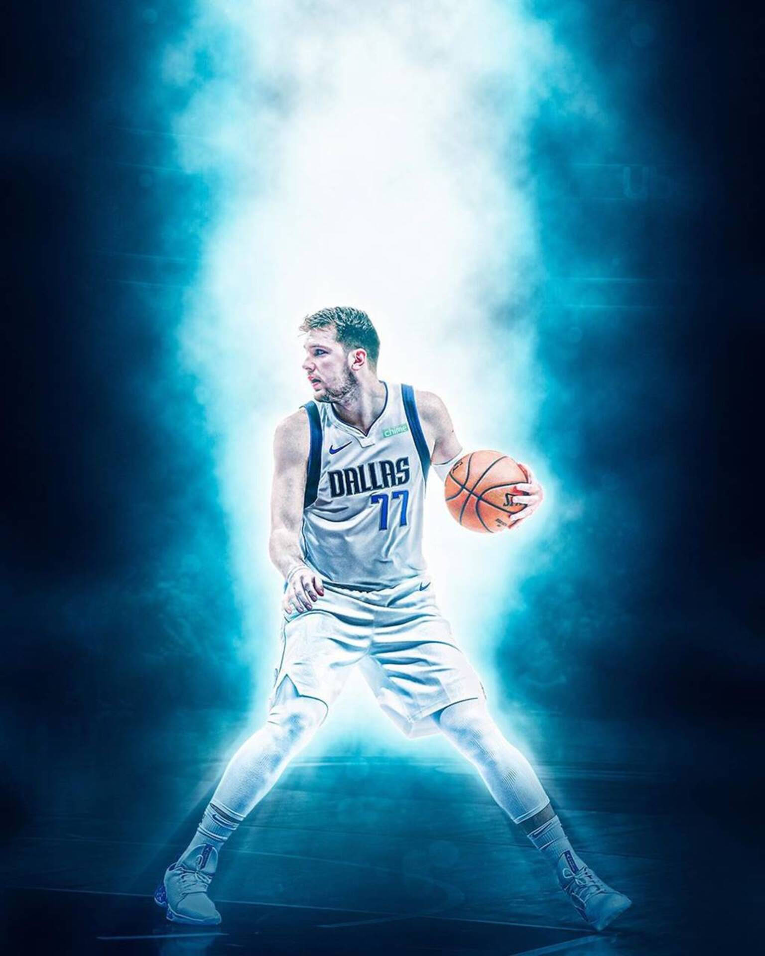 Luka 桌布 壁紙 — 一名身穿達拉斯球衣的籃球運動員在戲劇性的藍色舞台燈光和煙霧效果下持球。