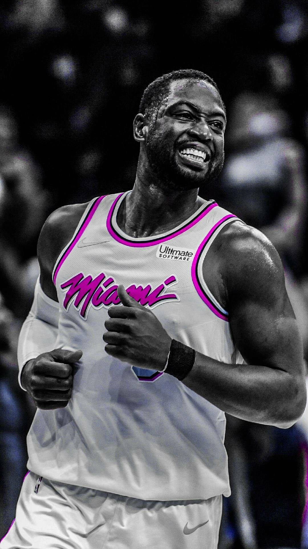 NBA 桌布 壁紙 — 一名身穿邁阿密球衣的籃球運動員在比賽中咧嘴大笑並豎起大拇指，身後是模糊的人群。