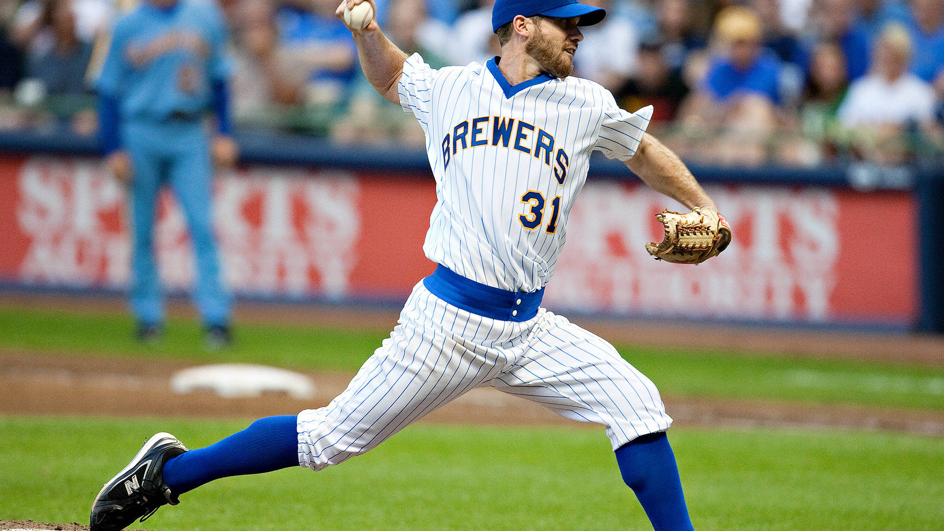 Brewers 桌布 壁紙 — 一名身穿釀酒人隊球衣的棒球投手在陽光明媚的球場上投球，背景有模糊的觀眾。