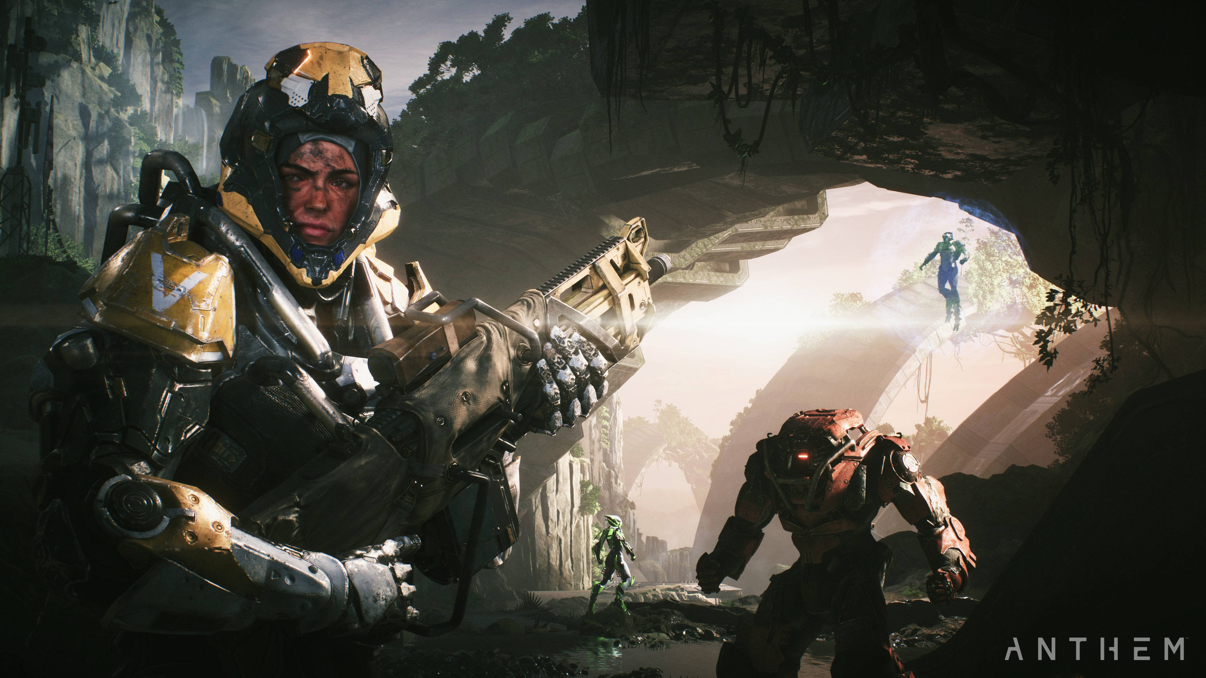 anthem 4K 桌布 壁紙 — 一名身穿重甲、戴著金色頭盔並手持武器的士兵站在黑暗的洞穴中，陽光從開口處射入，顯露出崎嶇峽谷景觀中的其他裝甲人物。