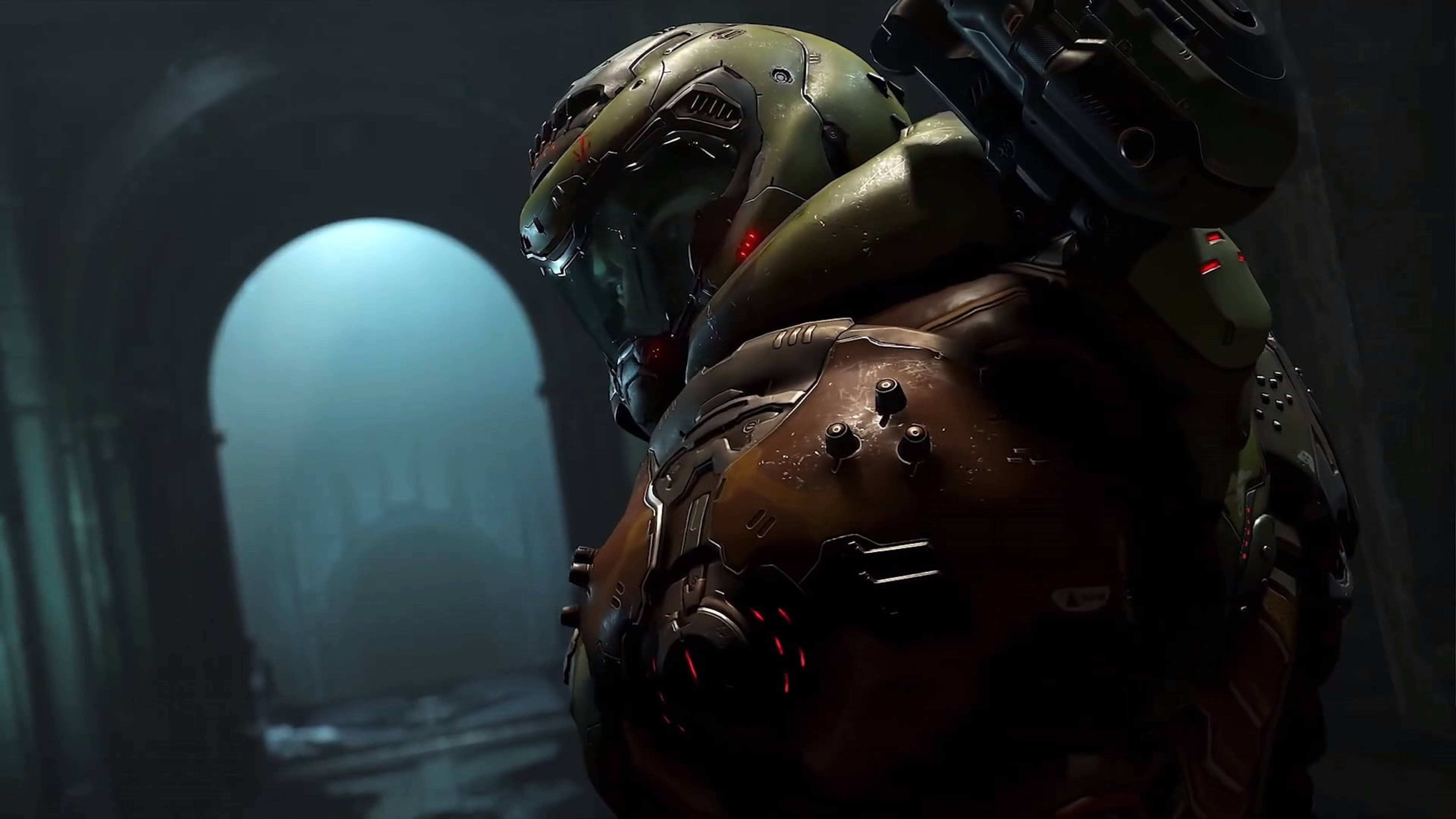 Doomguy 桌布 壁紙 — 一名身穿重甲的太空陸戰隊員站在昏暗的大教堂式走廊中，前方有一個發光的藍色拱門。