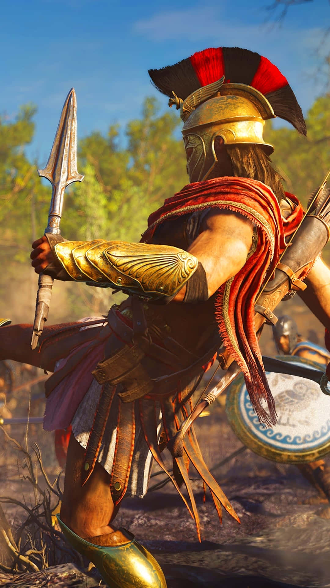 Android Assassin's Creed Odyssey 桌布 壁紙 — 一名身穿金色盔甲、頭戴紅色羽飾頭盔的斯巴達戰士，在陽光明媚的森林空地中準備好長矛和盾牌。