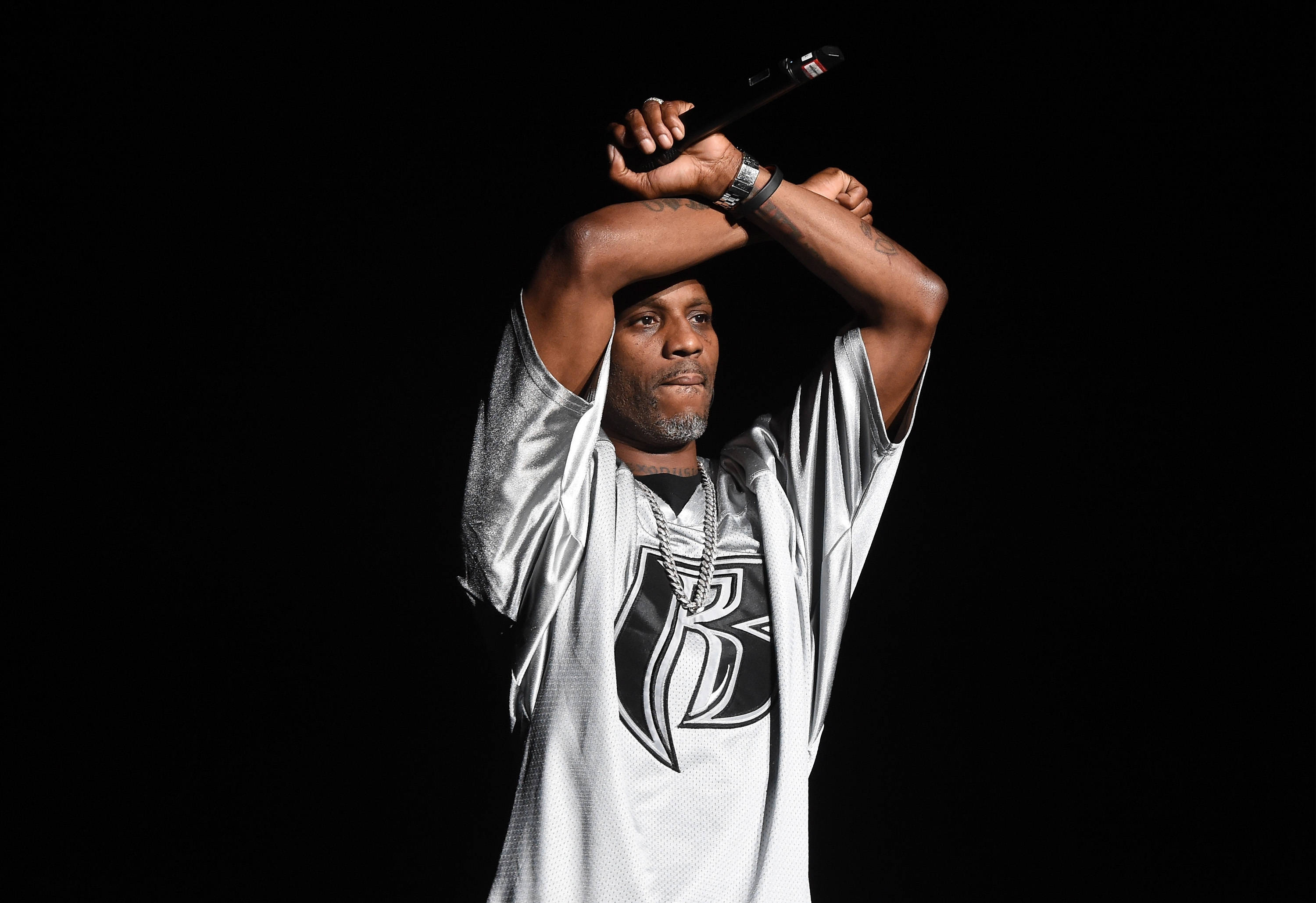 Dmx 桌布 壁紙 — 一名身穿銀色球衣的男子在黑色背景前將麥克風高舉過頭。