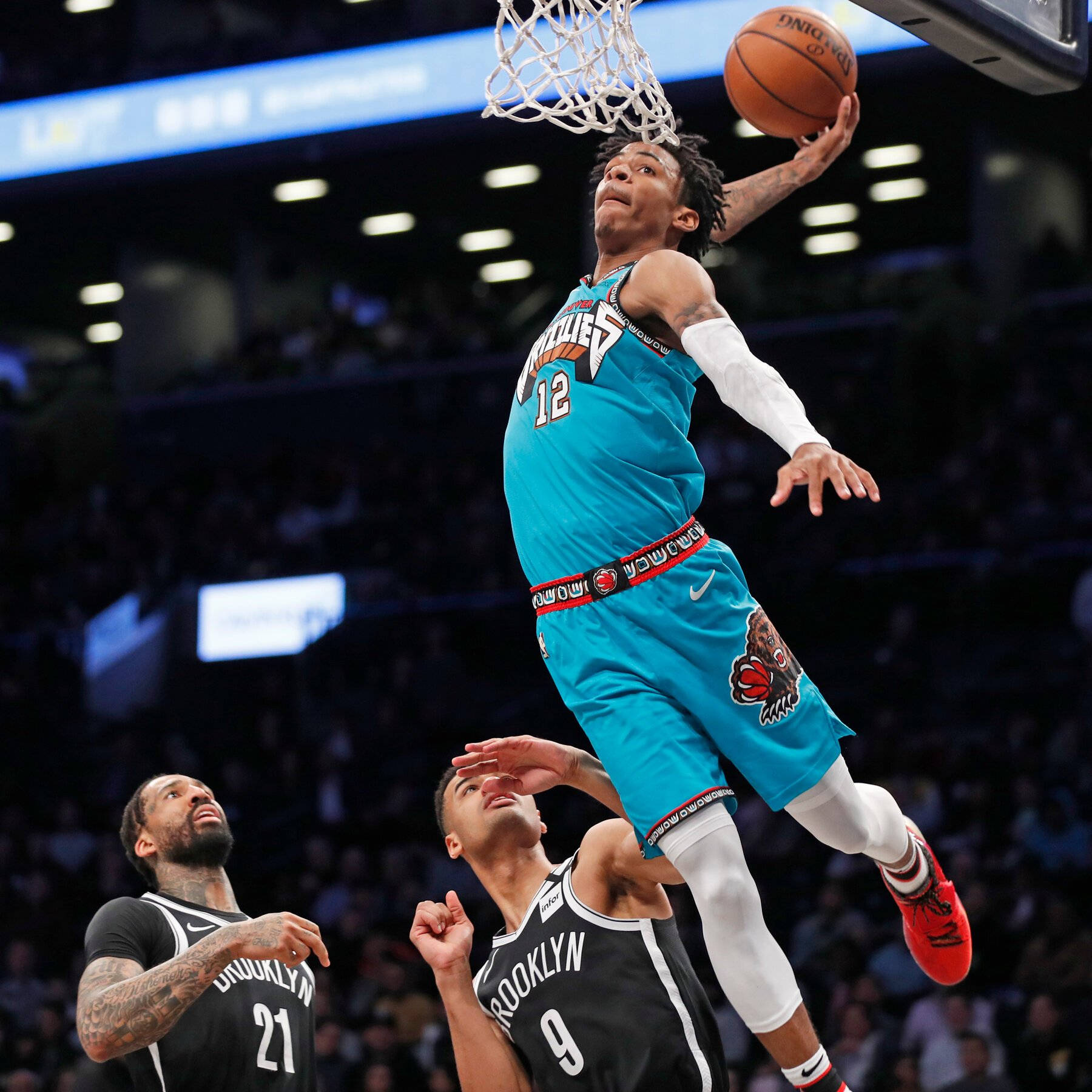 Ja Morant 灌籃 桌布 壁紙 — 一名身穿青綠色球衣的籃球運動員灌籃，兩名身穿黑色球衣的防守球員在下方觀看。