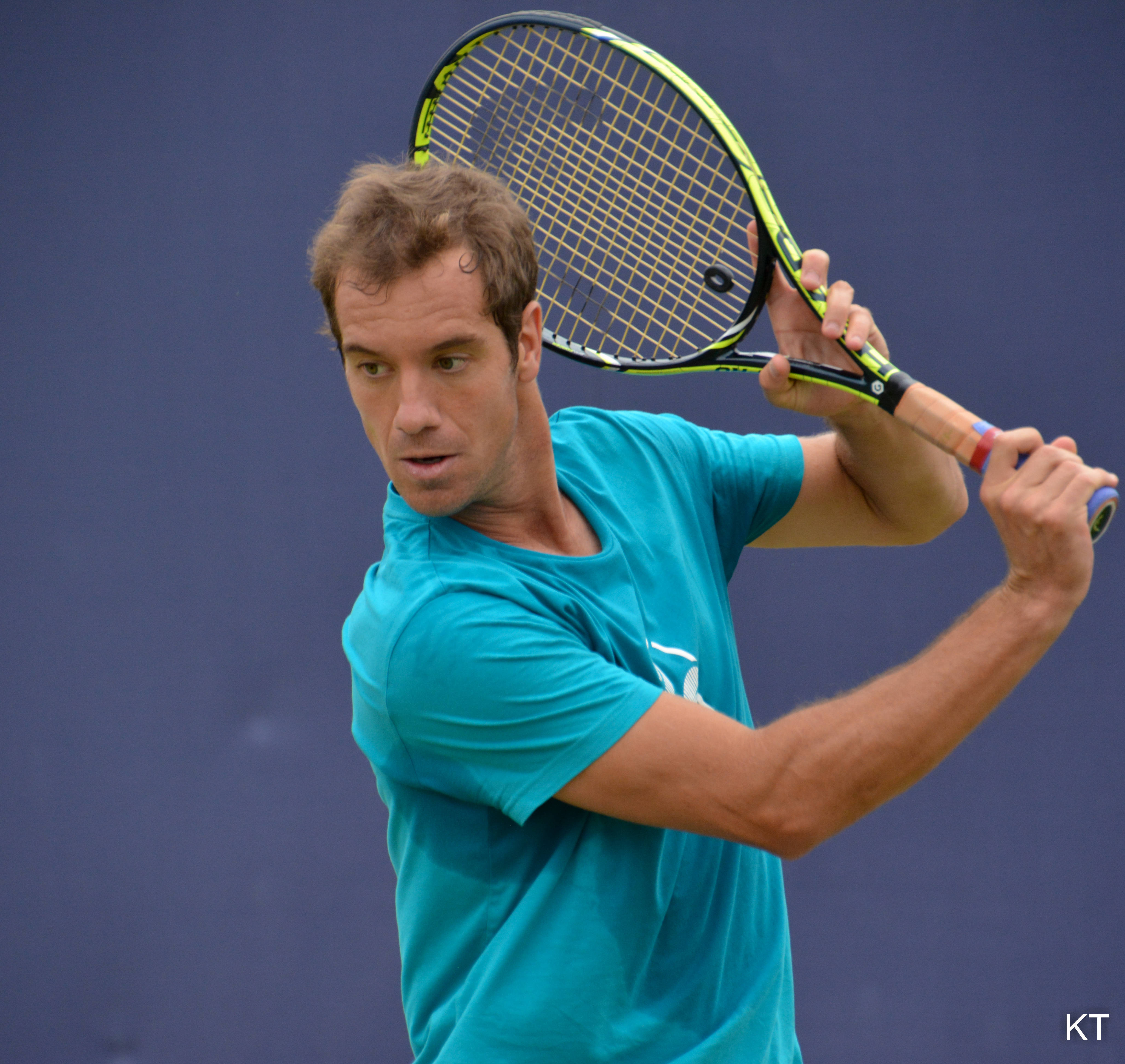 Tennis 桌布 壁紙 — 一名身穿青綠色襯衫的男性網球運動員，正揮動一支螢光黃色球拍，對著一面純藍色的牆壁。