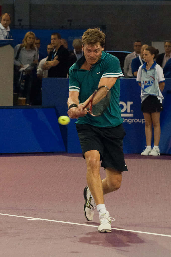 Tennis 桌布 壁紙 — 一名身穿青綠色襯衫的男性網球選手在室內比賽中，以高度專注力向前撲擊黃色球。