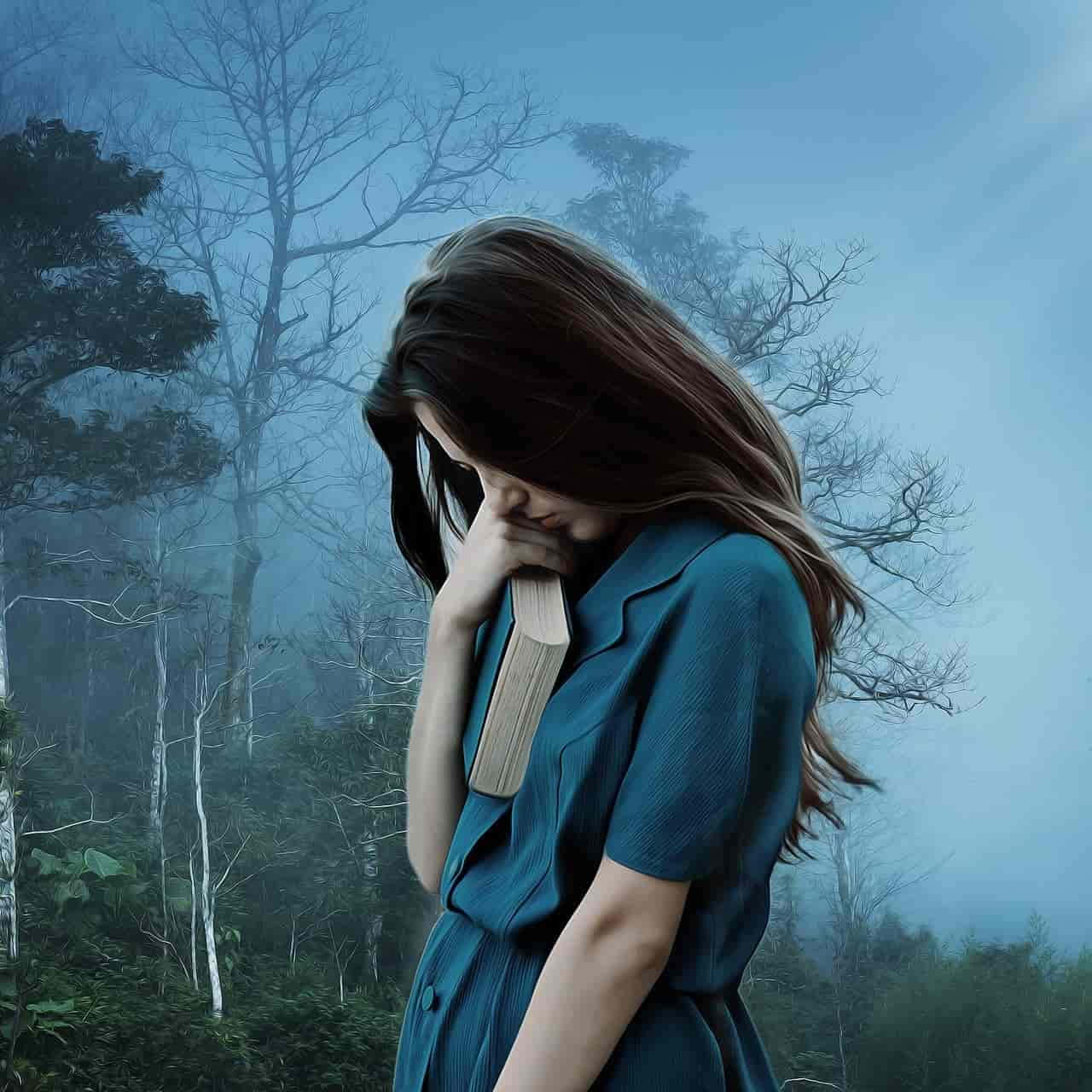 Depressing Profile 桌布 壁紙 — 一名身穿青綠色連衣裙的女子在霧氣瀰漫的樹林中，光禿的樹木下，淡藍色的天空下，將一本書貼在臉上。