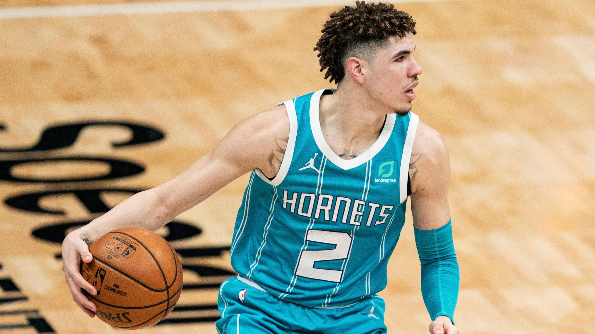 Hornets 桌布 壁紙 — 一名身穿青綠色黃蜂隊球衣的籃球運動員在木地板上專注地運球。