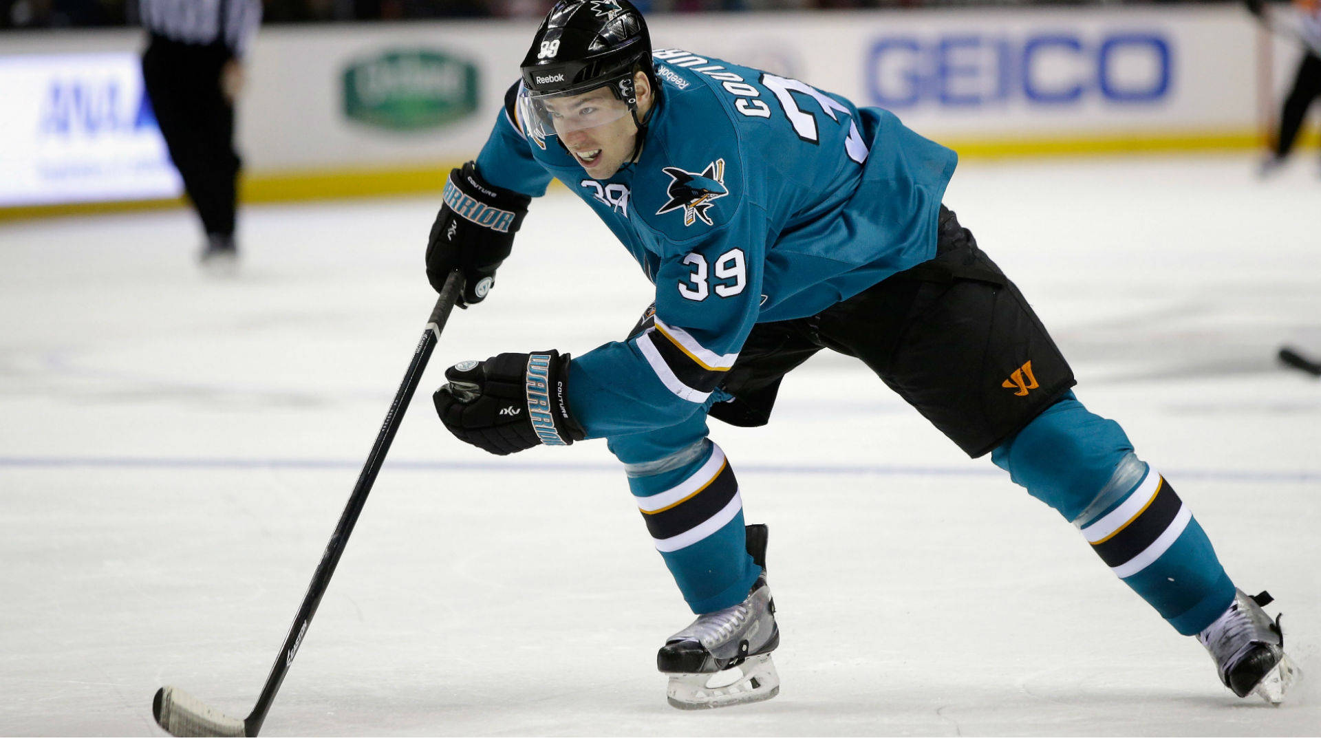 hockey 桌布 壁紙 — 一名身穿青色鯊魚隊39號球衣的冰球運動員在比賽中在冰上激烈前傾。