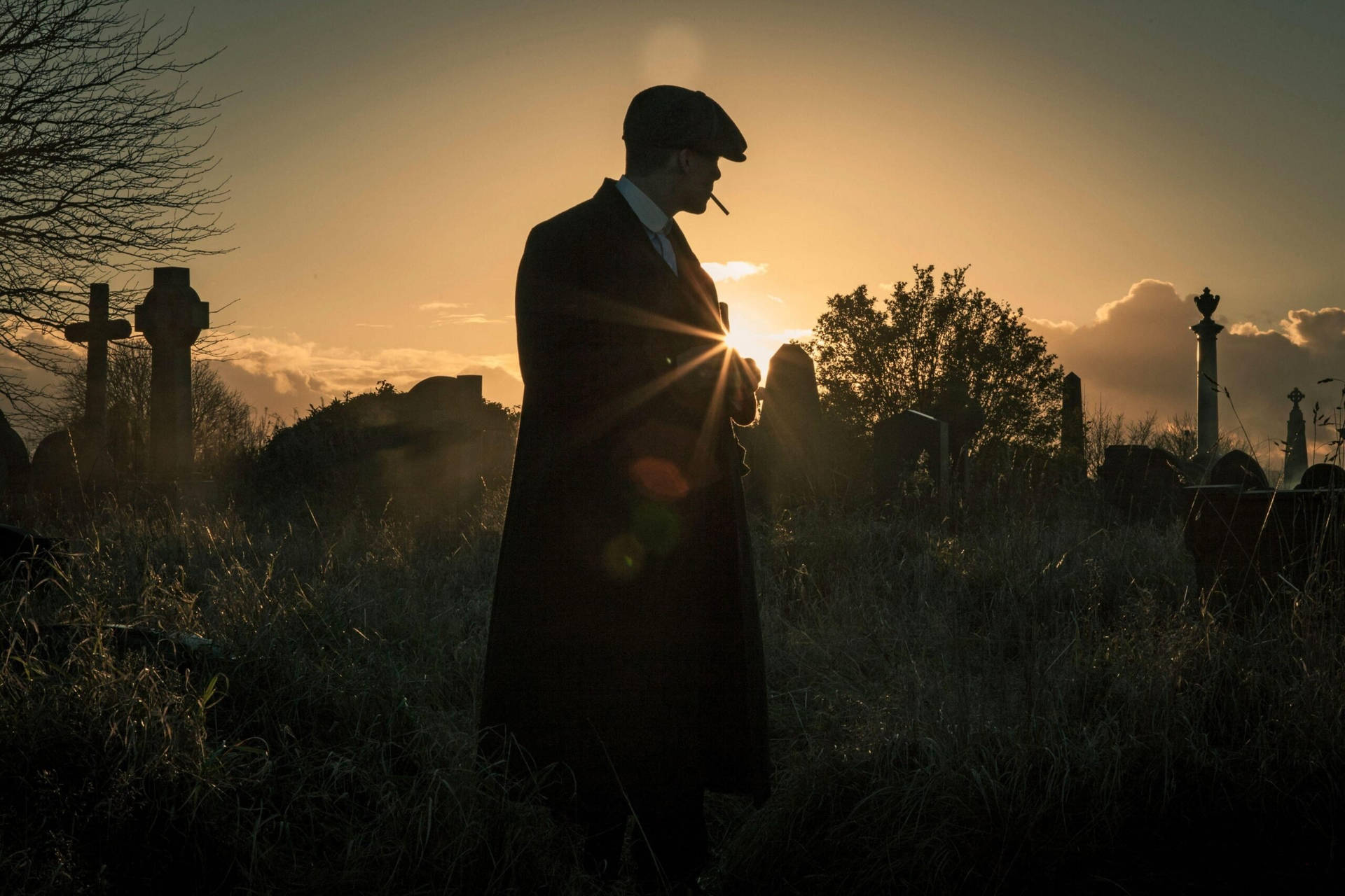 身穿風衣的男子在墓園日落時抽煙。 — Peaky Blinders 壁紙